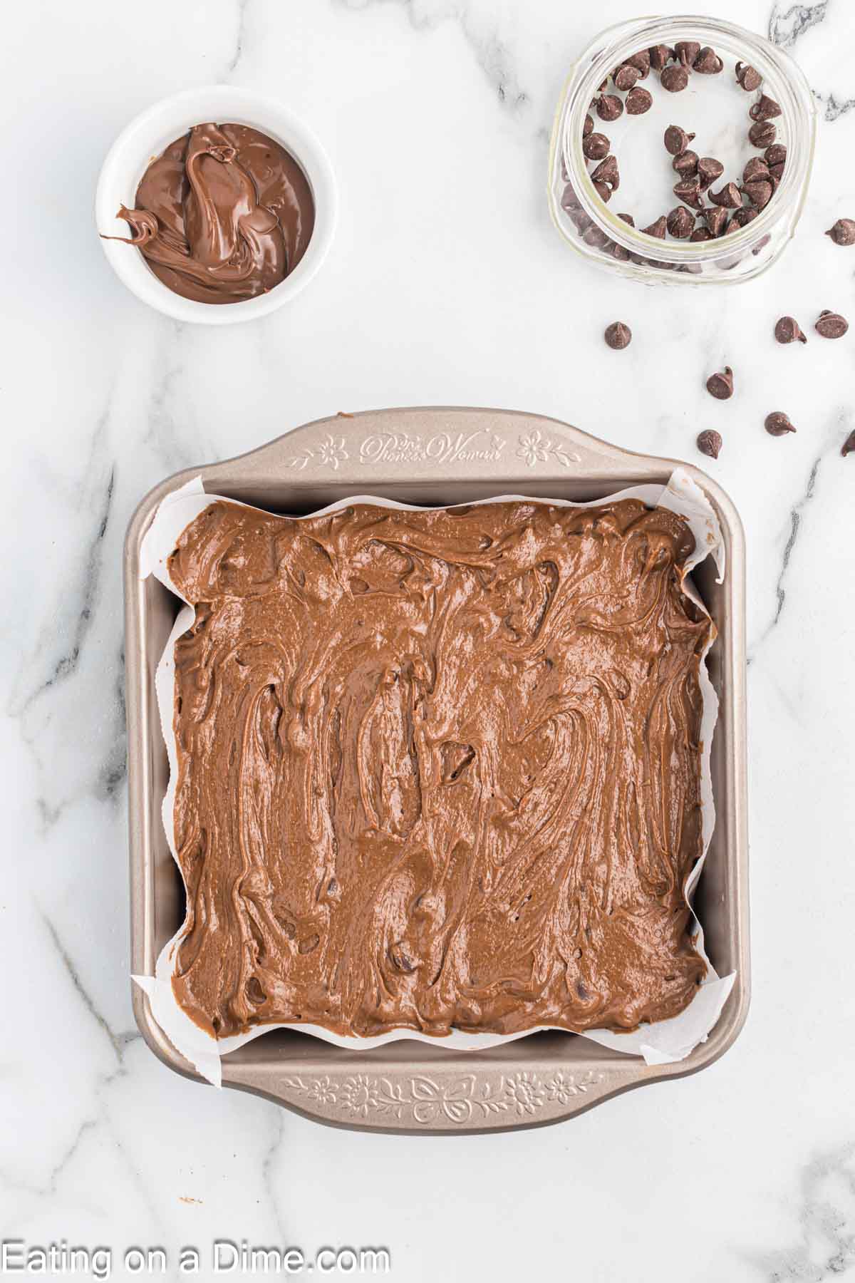 Spreading Nutella Brownie Mixture in a baking dish with small bowl of Nutella