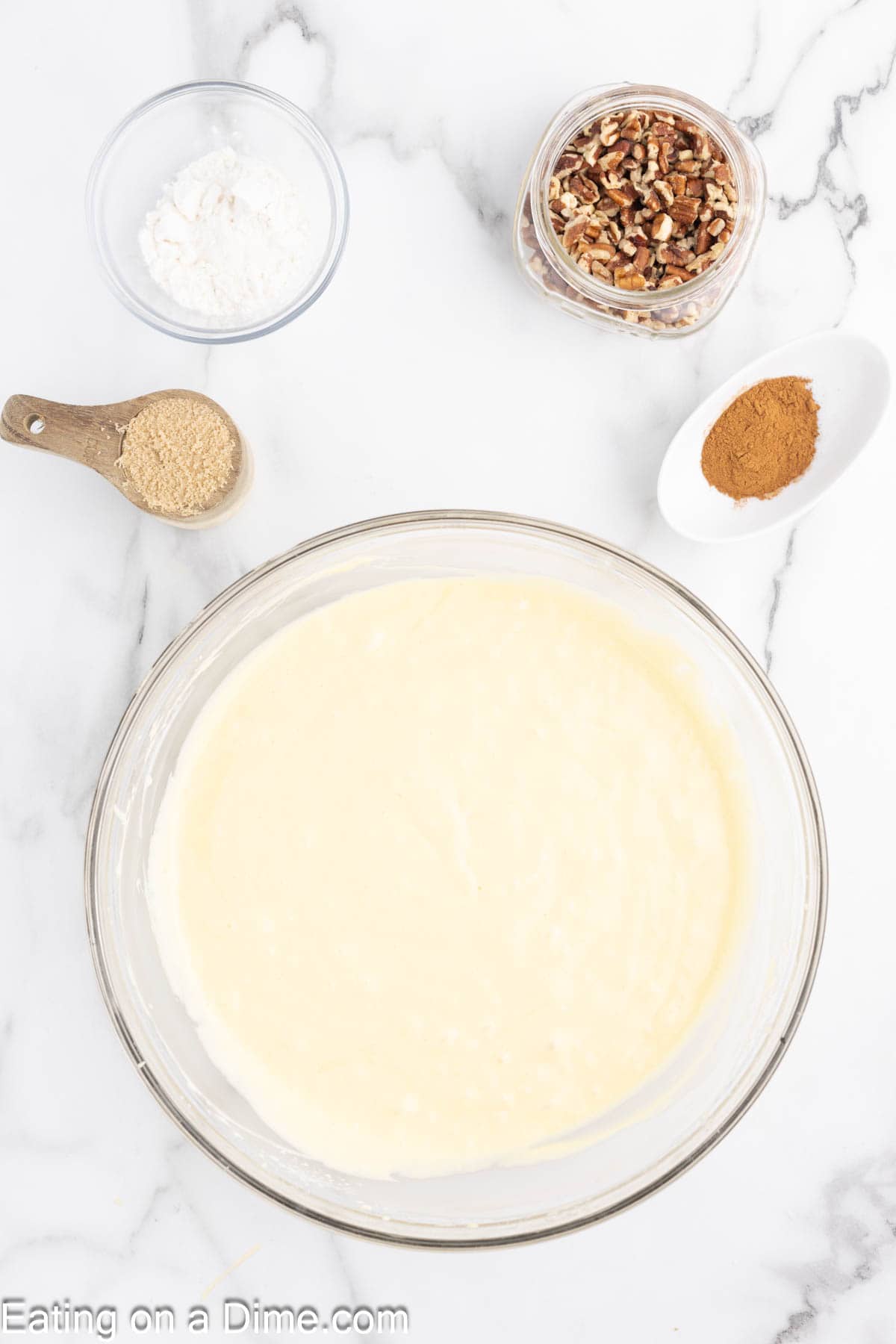 Cake Mix batter in a bowl with small bowls of powdered sugar, pecans, cinnamon and brown sugar on the side