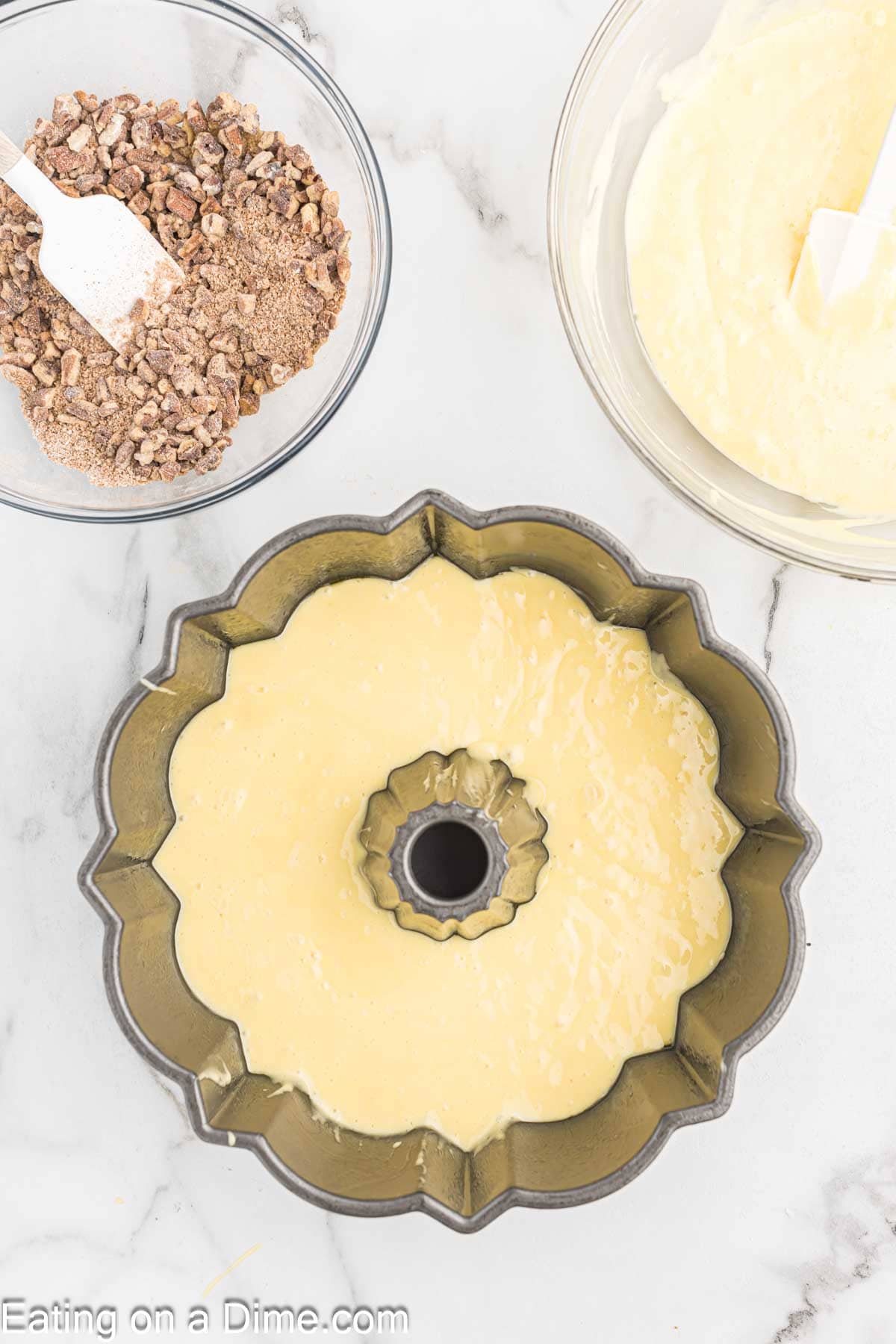 Cake Mix batter poured into bundt pan, small bowl of pecan mixture on the side