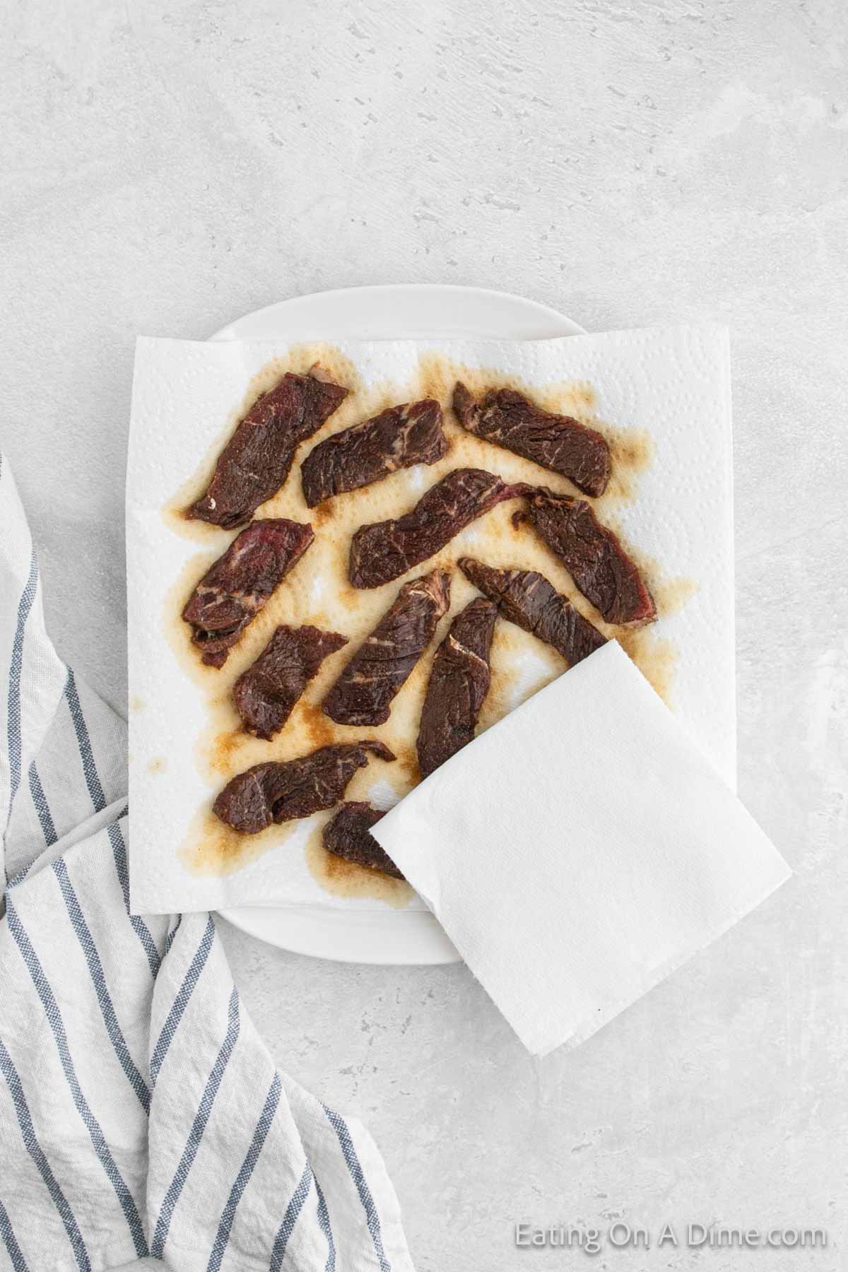 Drying the beef strips on a paper towel lined plate