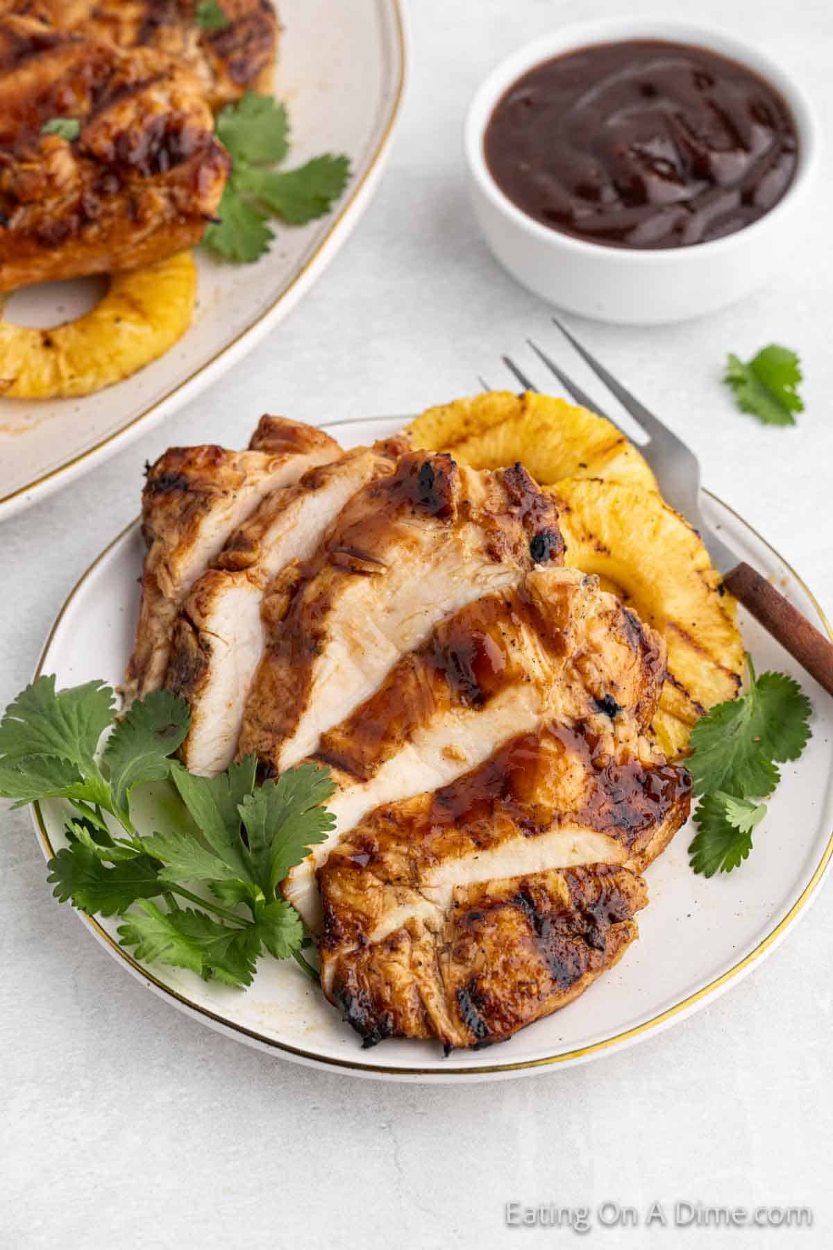 BBQ Chicken sliced on a plate with a side of grilled pineapple slices on a plate