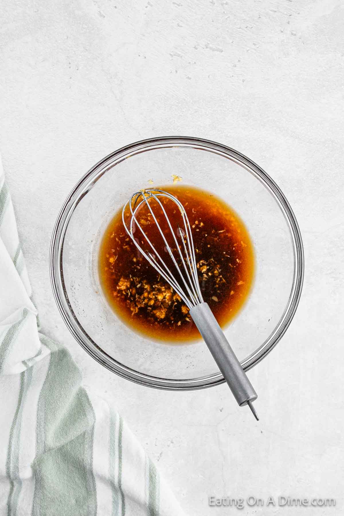 Combining pineapple juice, soy sauce, honey, garlic, ginger in a bowl with a whisk