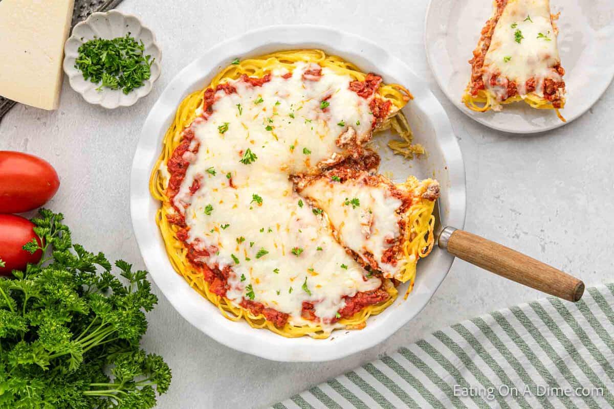 Spaghetti Pie in a pie plate with a serving cut on a spatula