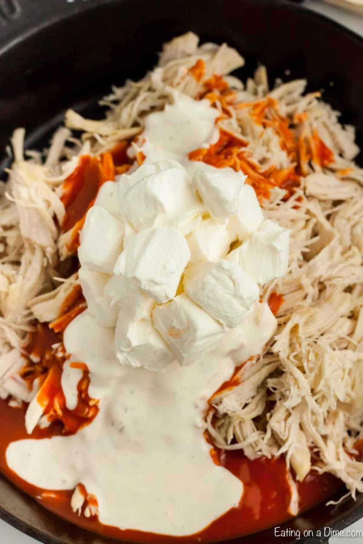 Shredded chicken topped with buffalo sauce and cream cheese cubes