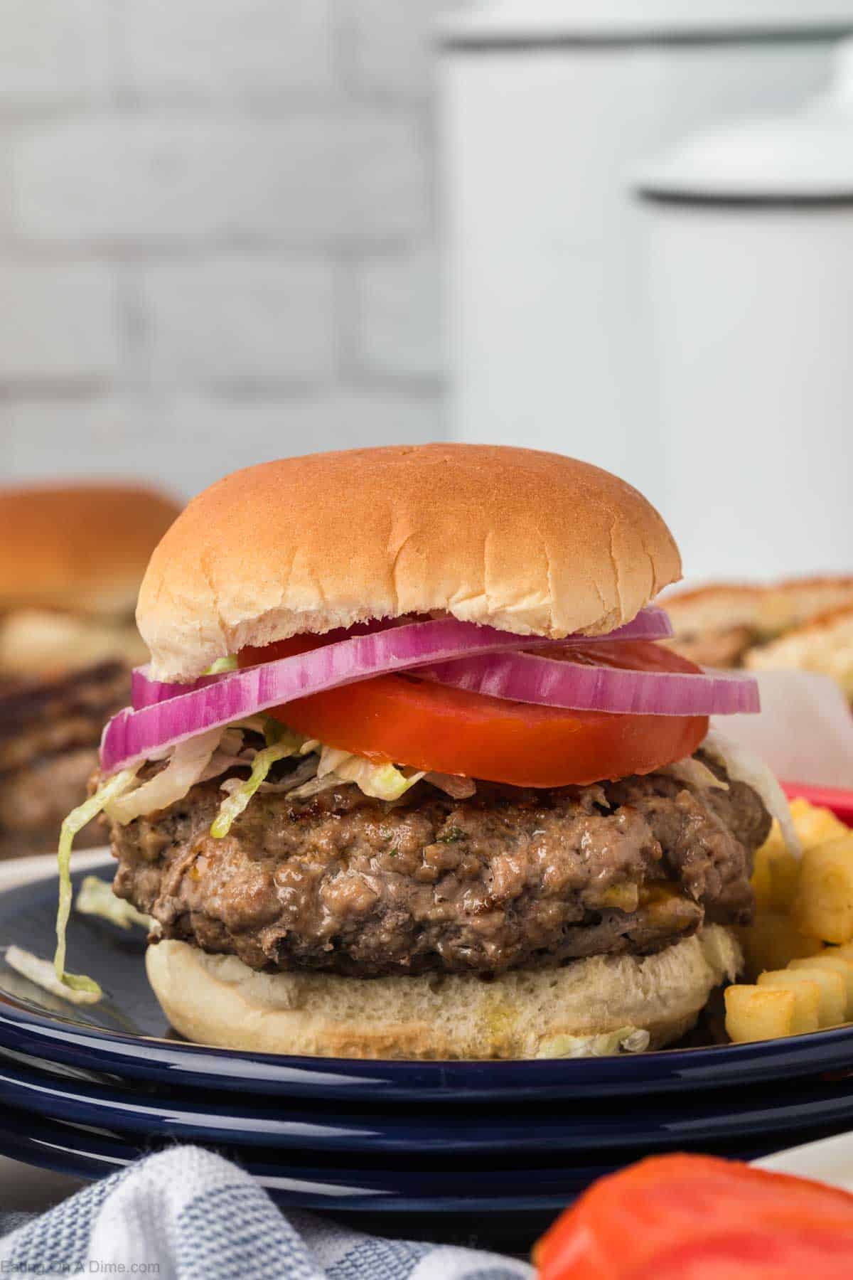 Crack Burgers on a plate topped with red onions and slice tomatoes