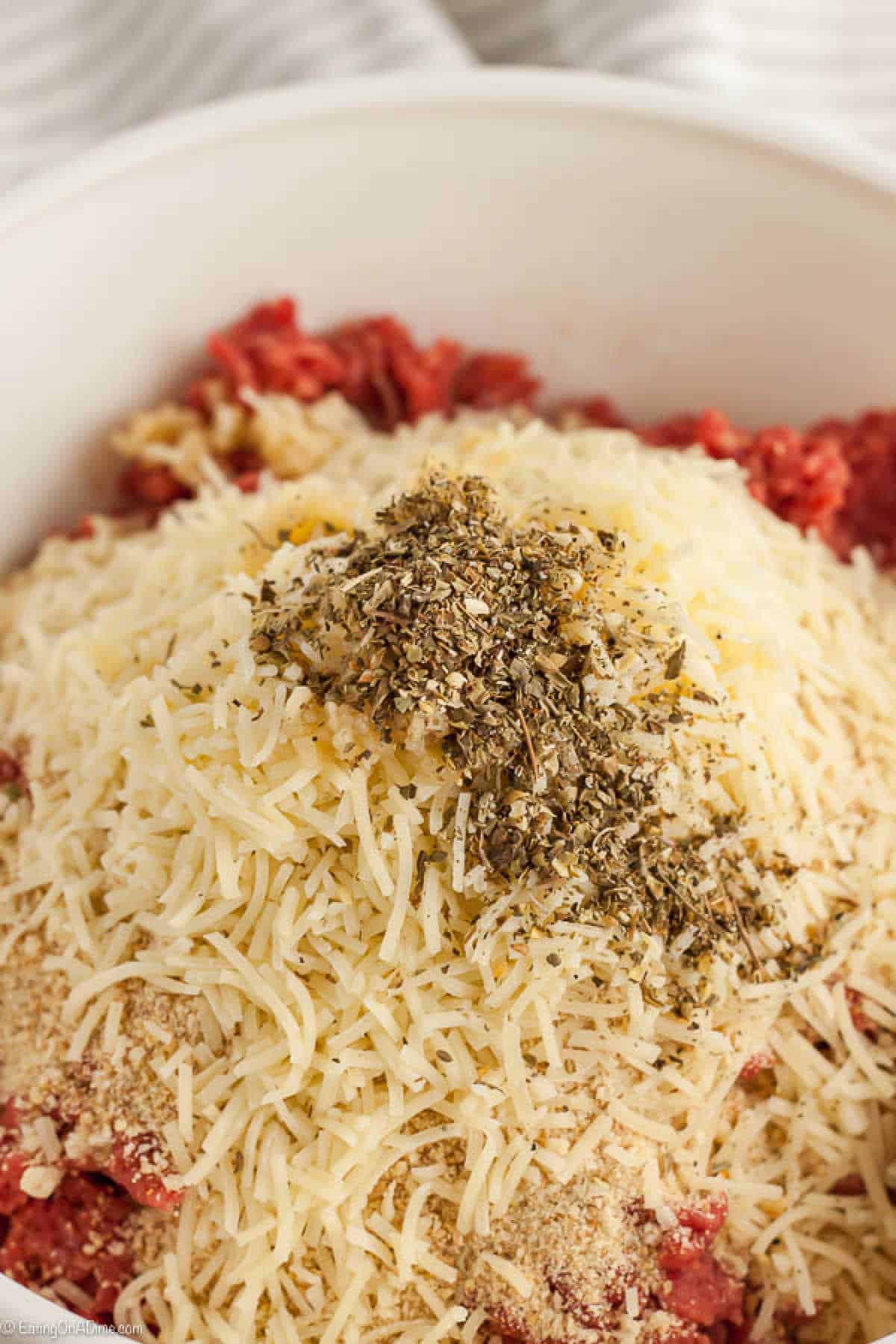 Ground beef in a bowl topped with shredded cheese and seasoning