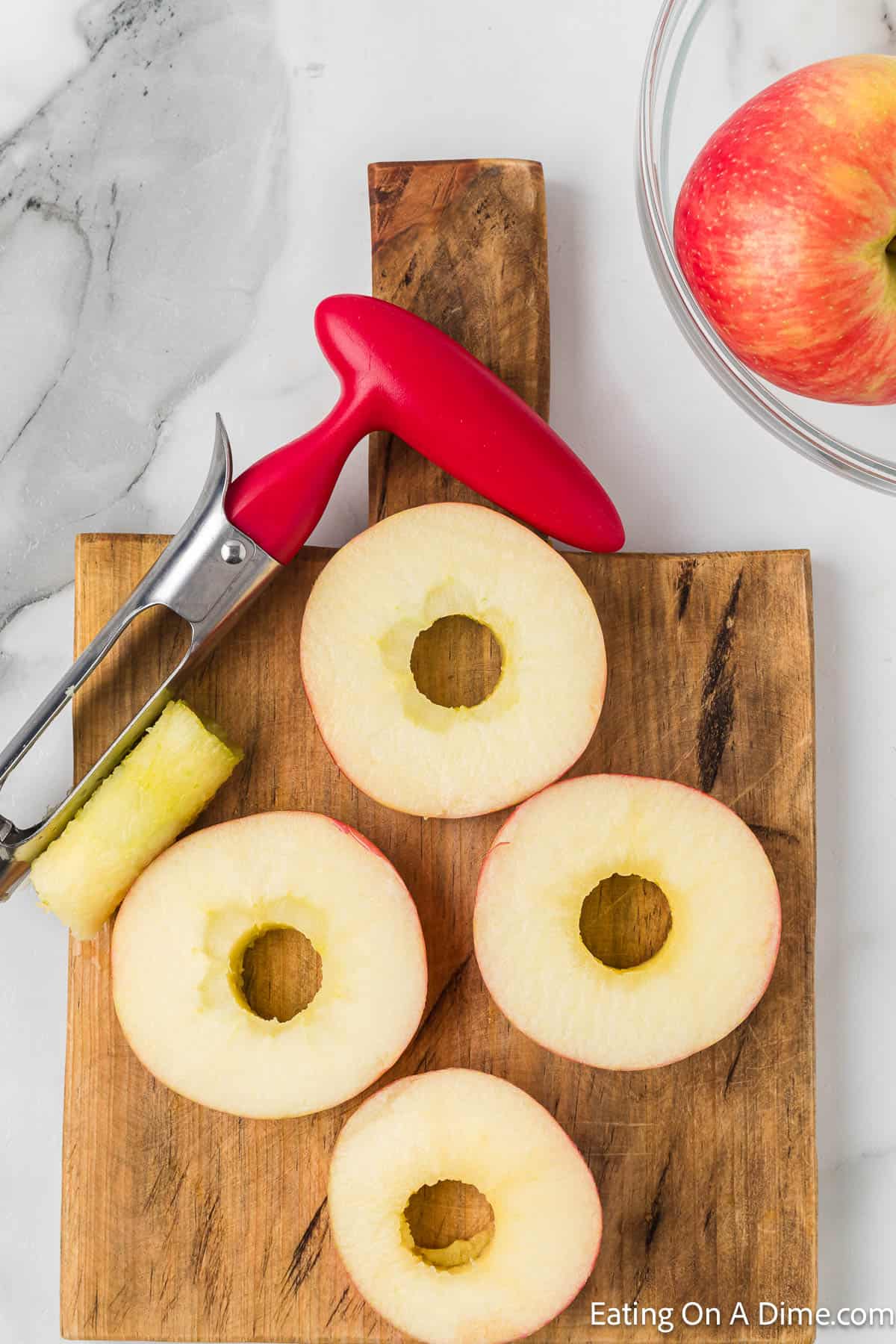 Apple corer with slices of apples on a cutting board