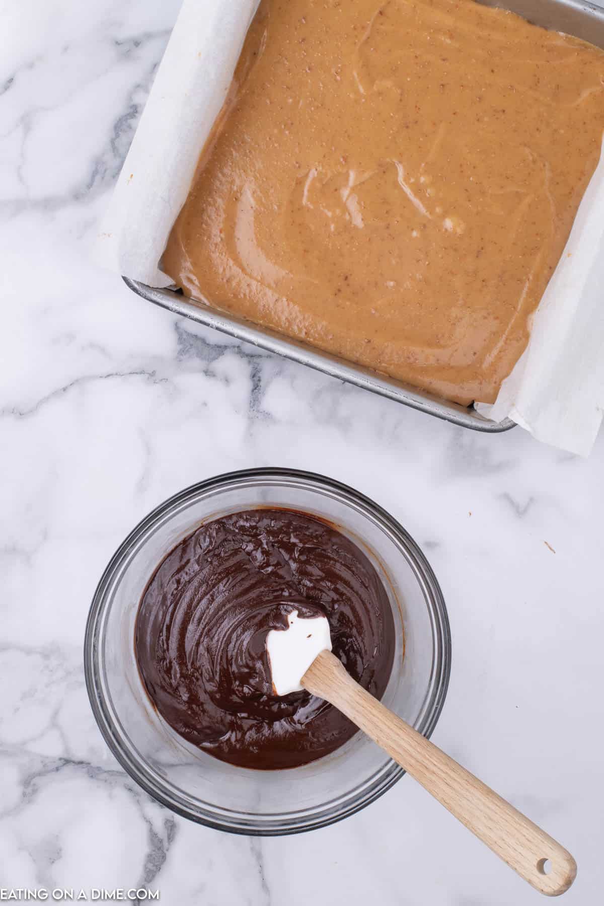 Melted chocolate in a bowl with a spatula and a baking dish with the caramel layer