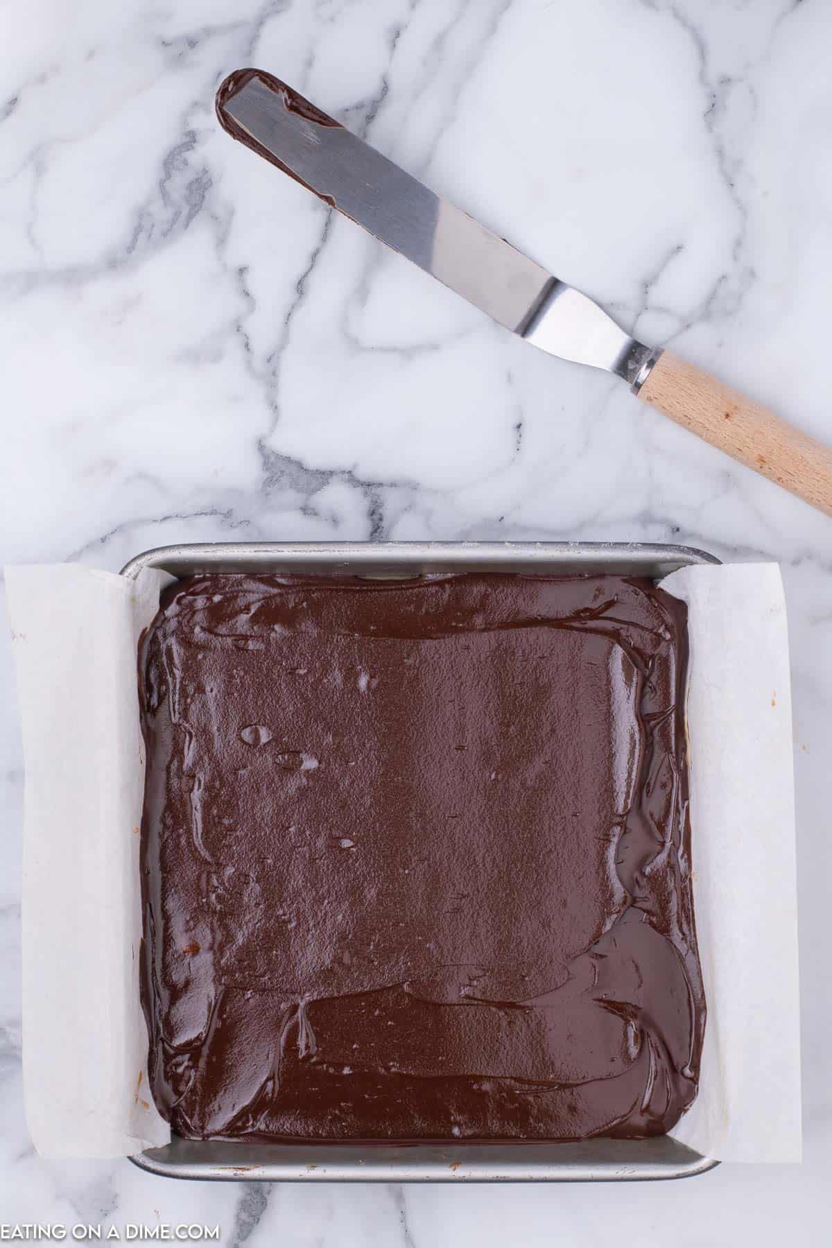 Chocolate layer in the baking dish lined with parchment paper