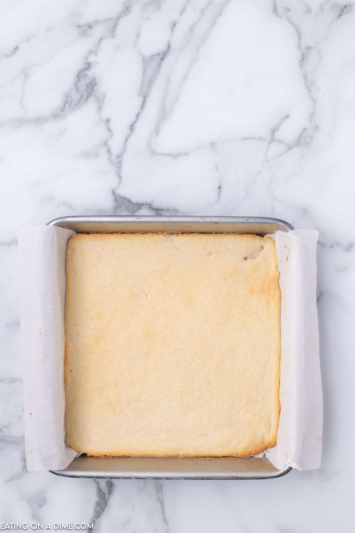 Baked shortbread crust in a baking dish lined with parchment paper