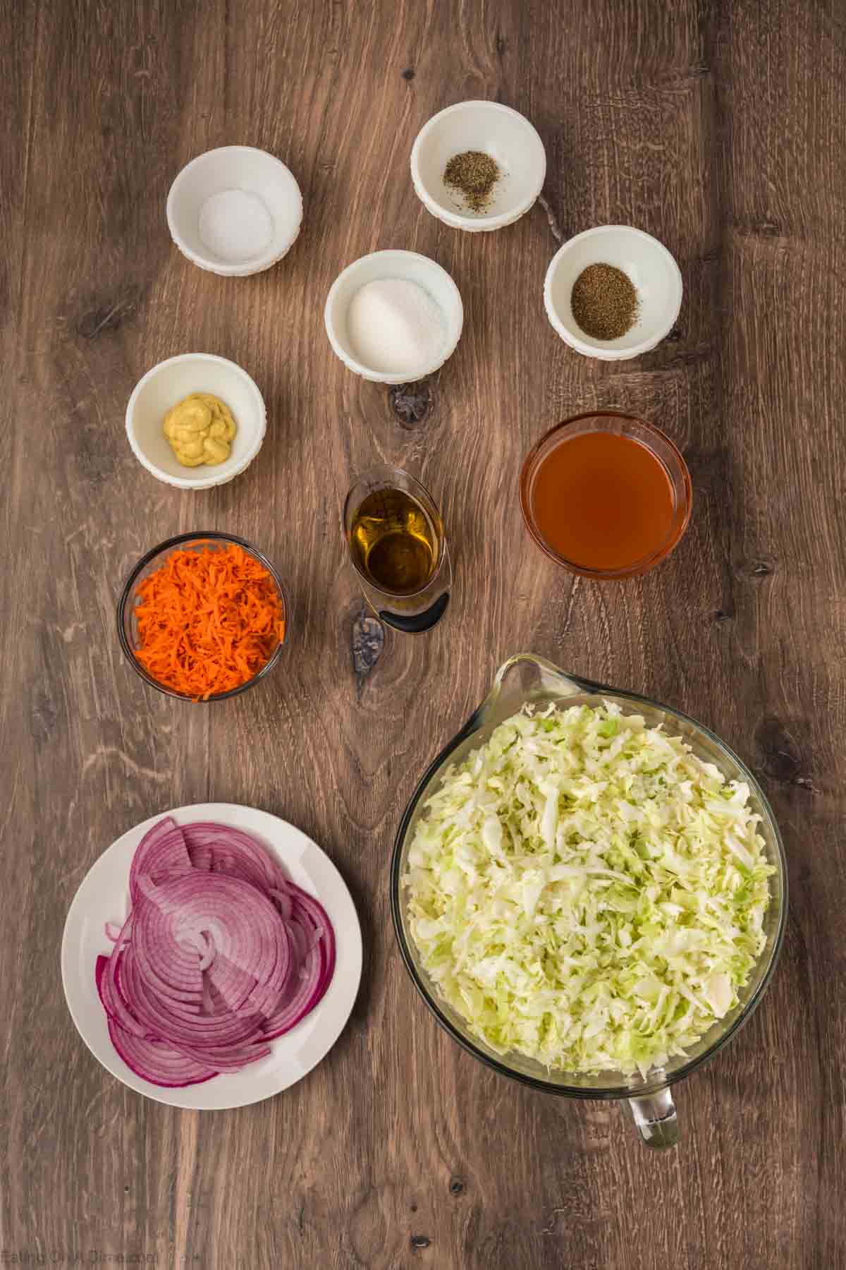 Green Cabbage finely shredded in a bowl, carrot, red onion, apple cider vinegar, sugar, dijon mustard, celery seeds, salt, pepper, oil