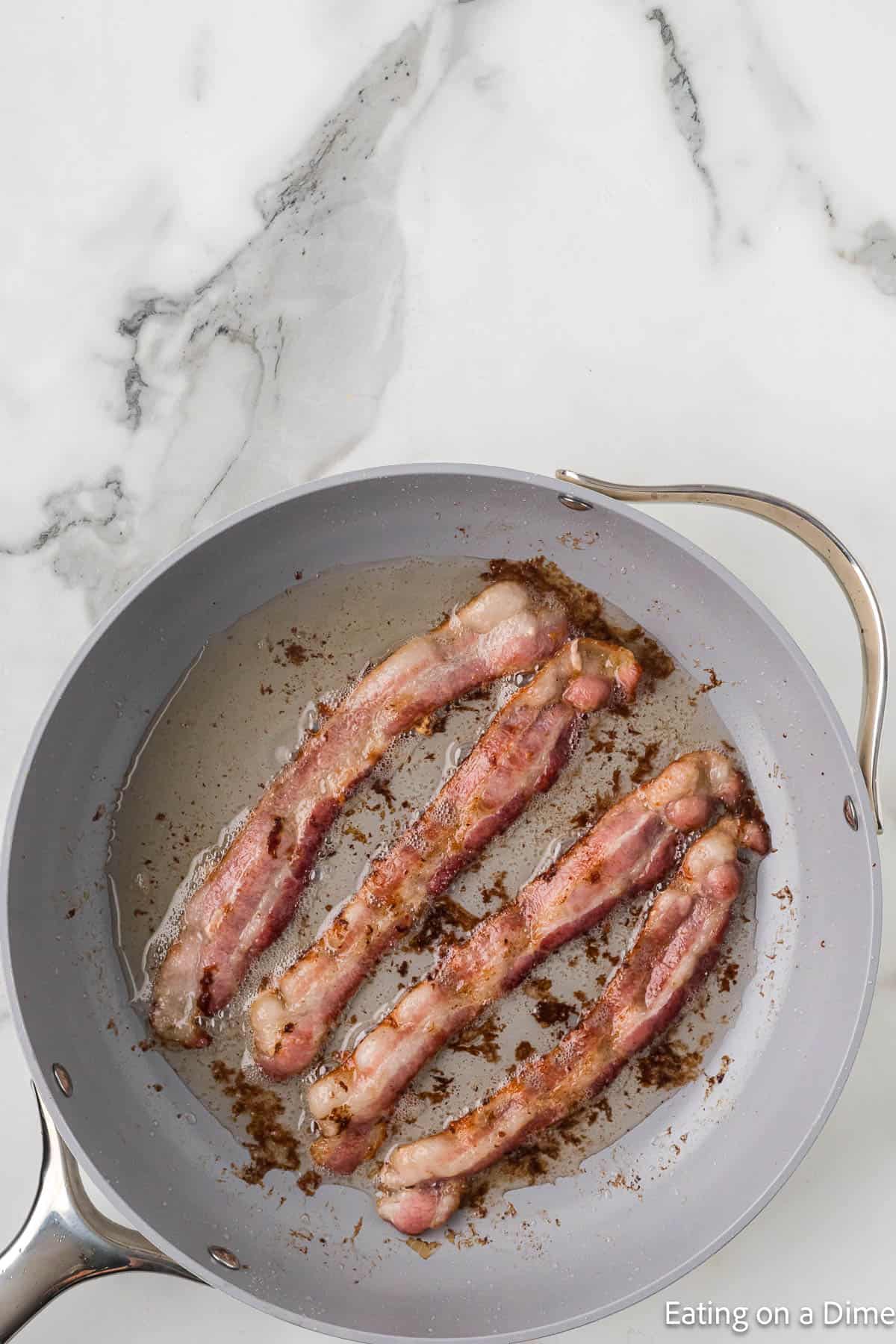 Slice of bacon cooking in a frying pan