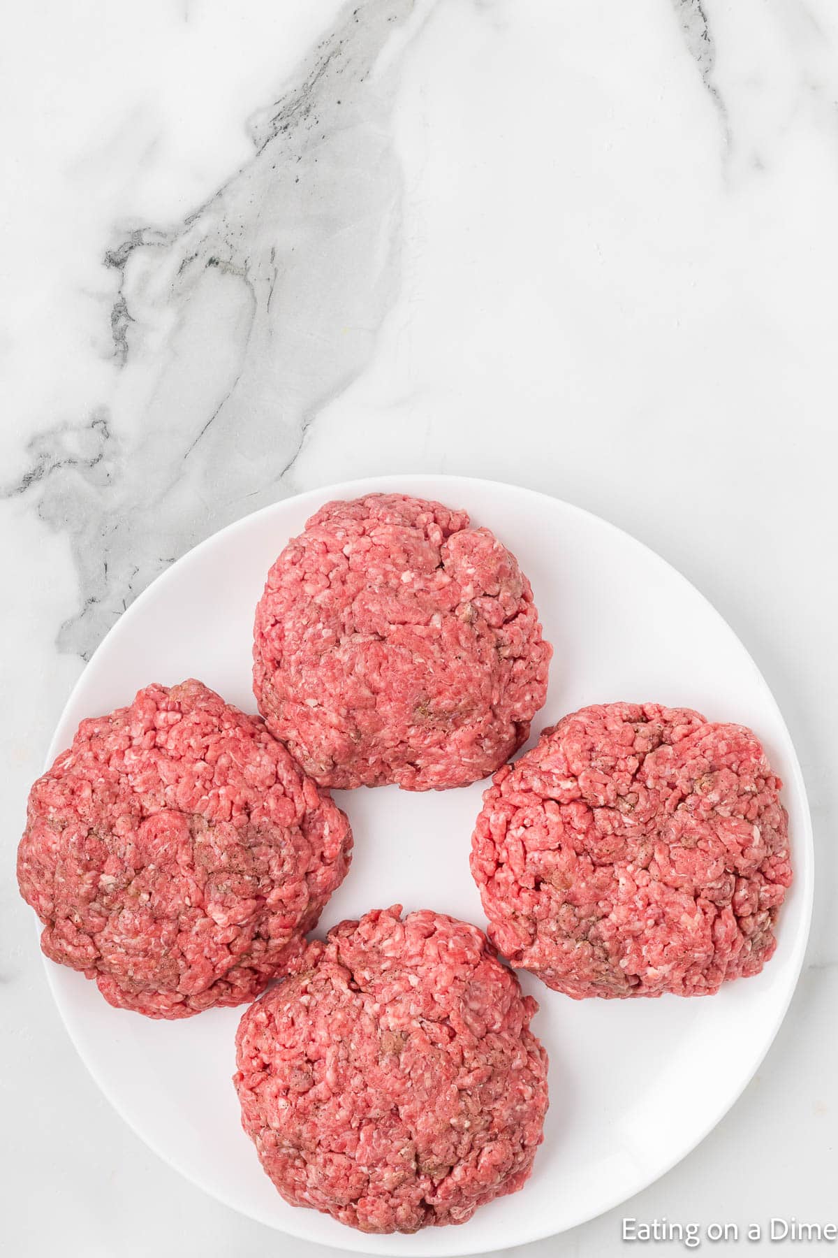 4 Ground beef Patties on a white plate