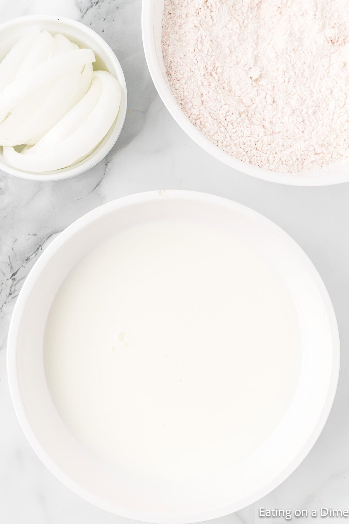 Bowl of onions, buttermilk, and flour in a bowl