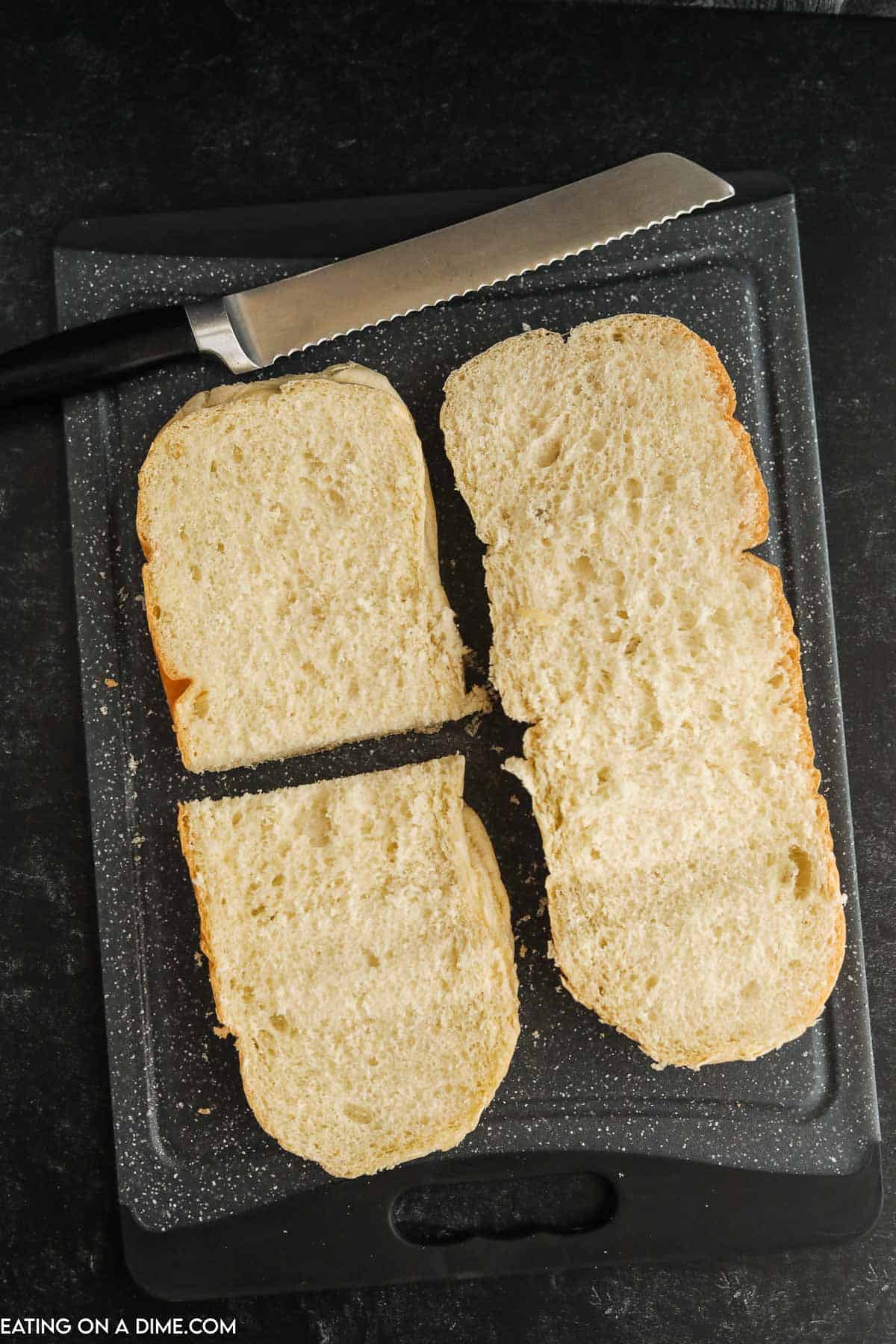 French Bread cut in half on a cutting board with a knife