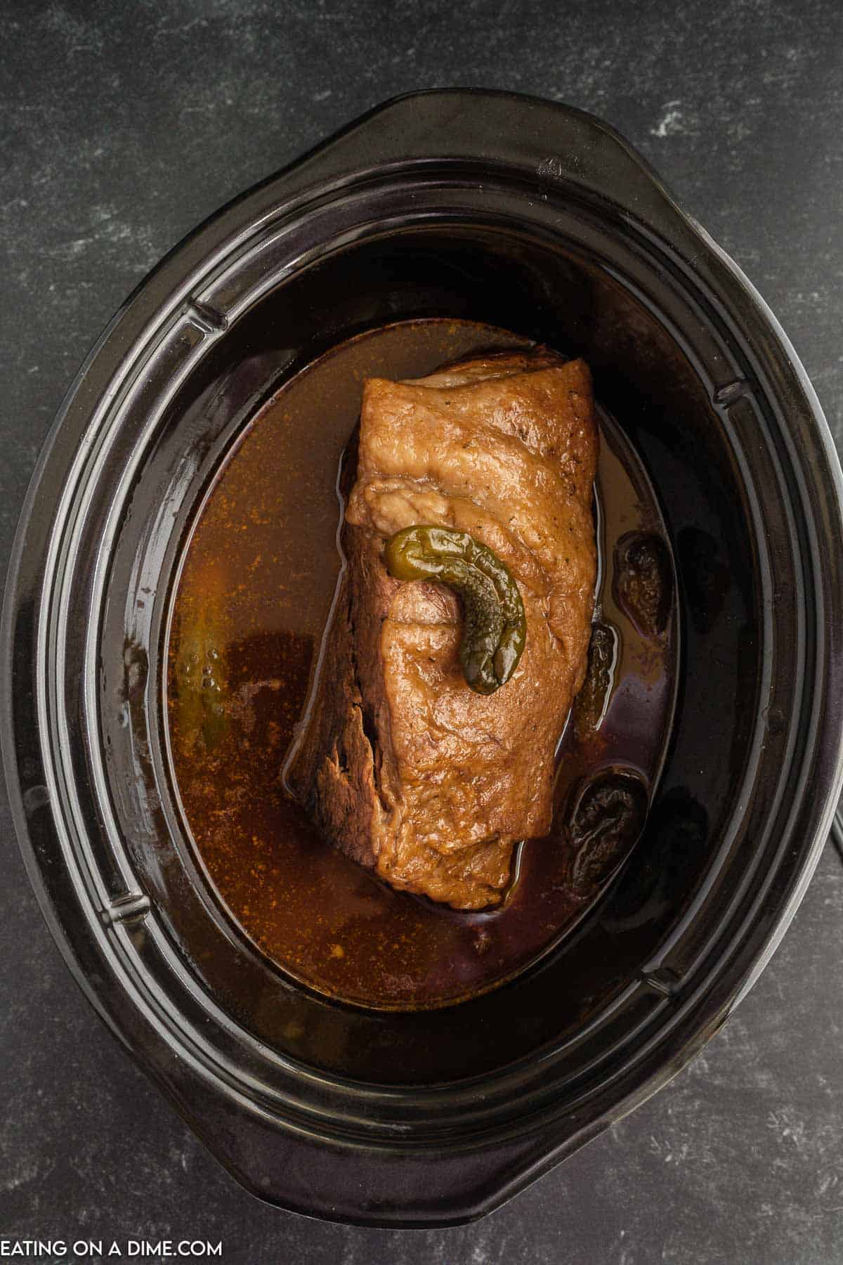 Cooked roast in sauce with pickles in the slow cooker