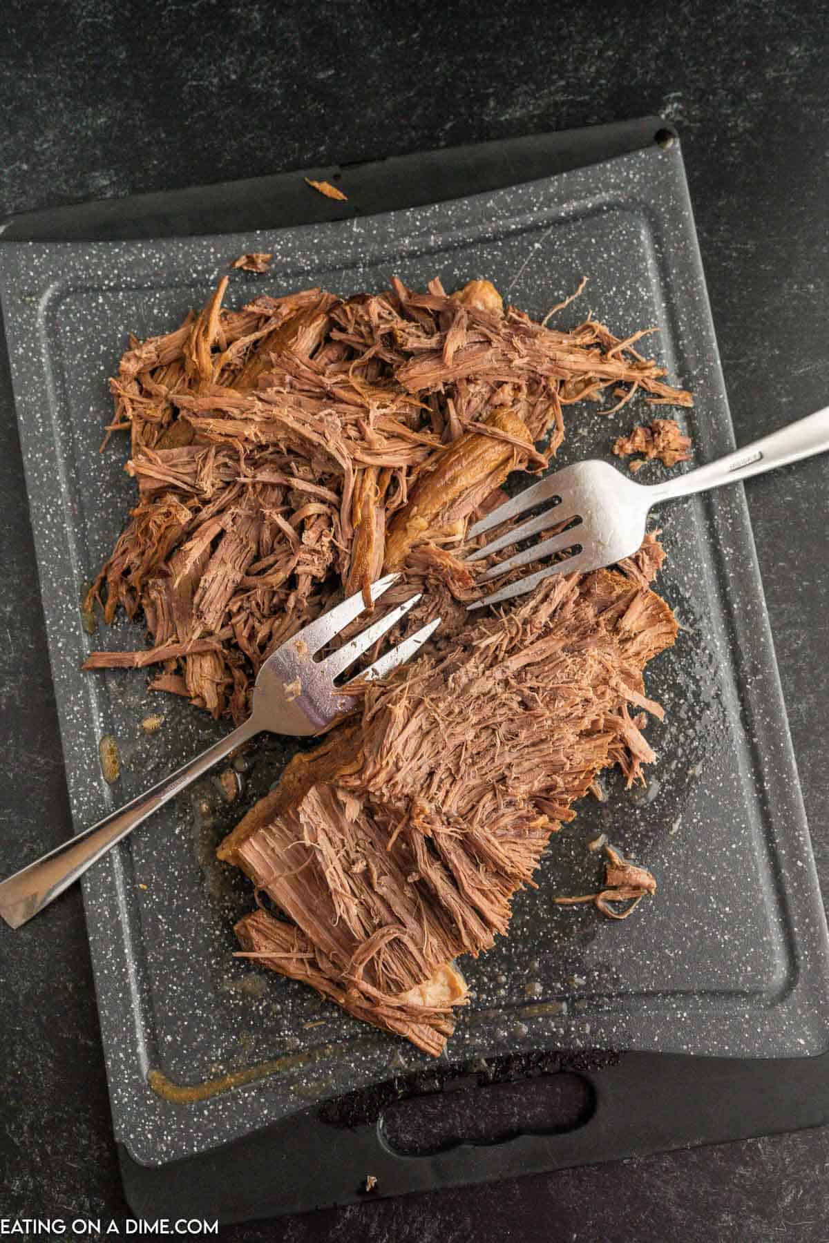 Shredded meat on the cutting board with two forks