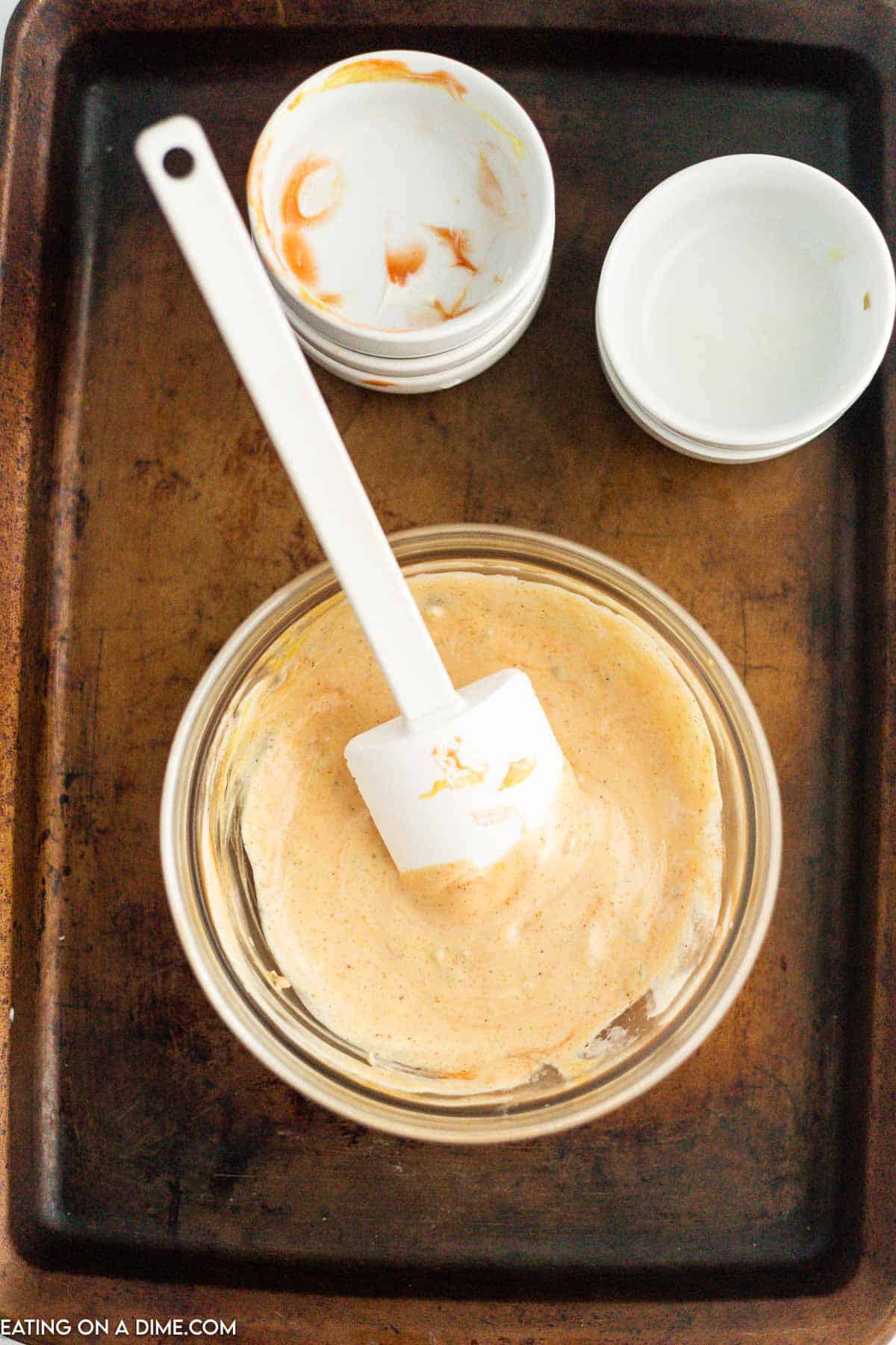 Combining the sauce ingredients in a bowl with a spatula with small empty bowls on the side