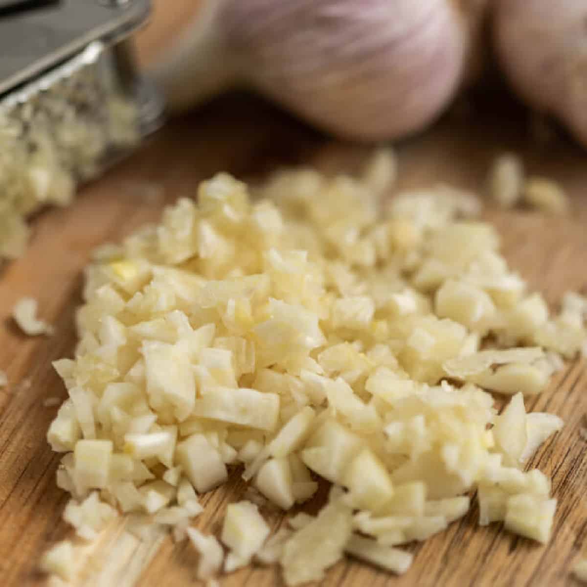 Close up image of chopped garlic cloves on a cutting board. 
