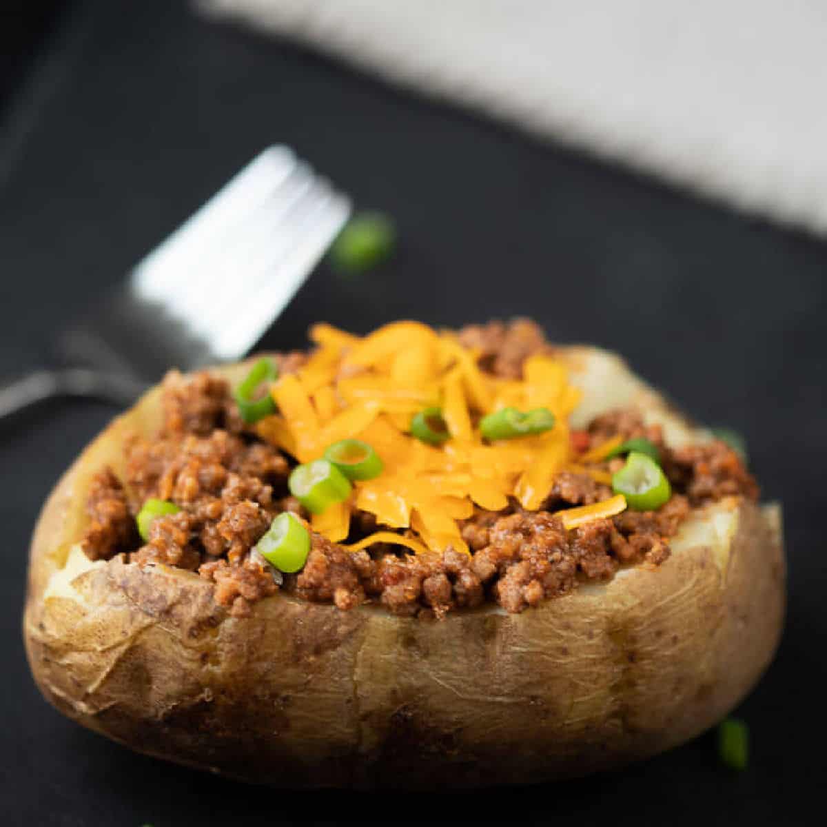 Bake potato topped with ground beef, shredded cheese and green chives