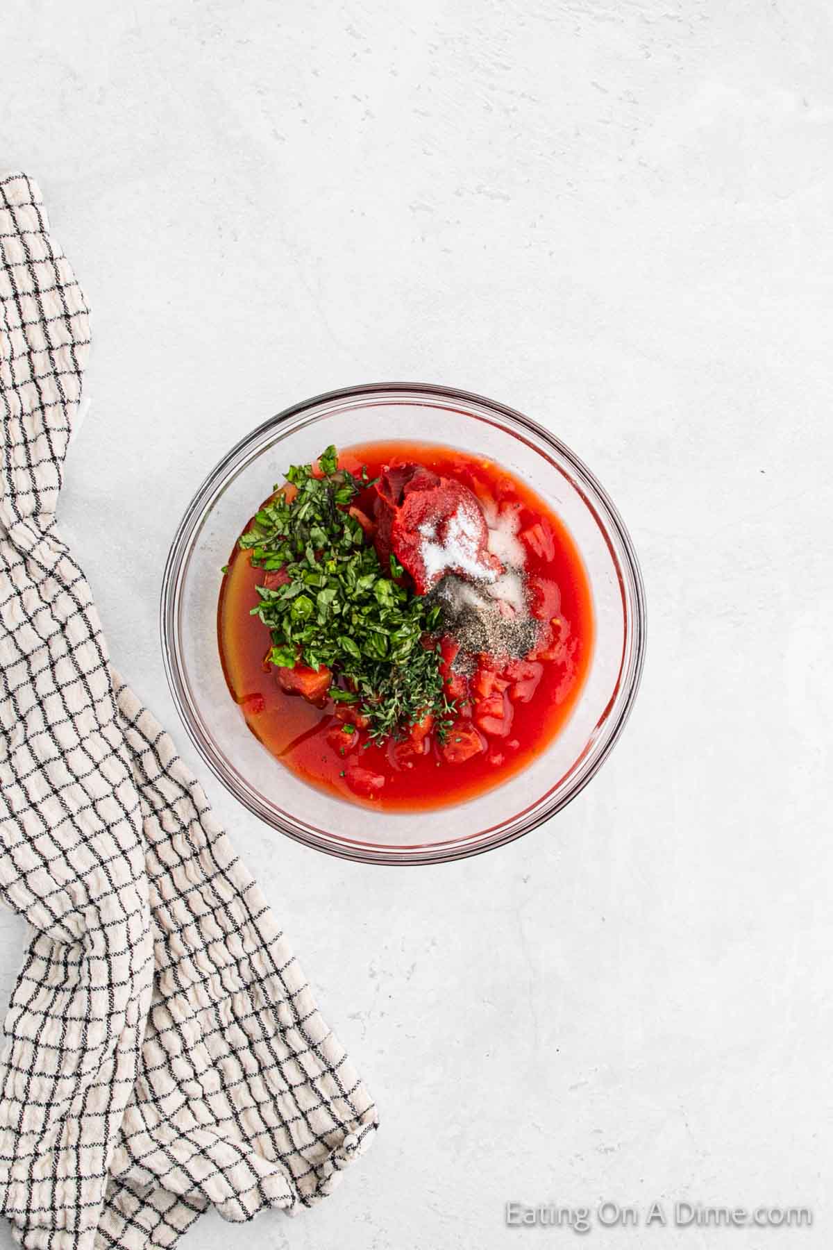 Diced tomatoes with juice mixed with basil, thyme, oil, salt and pepper in a bowl