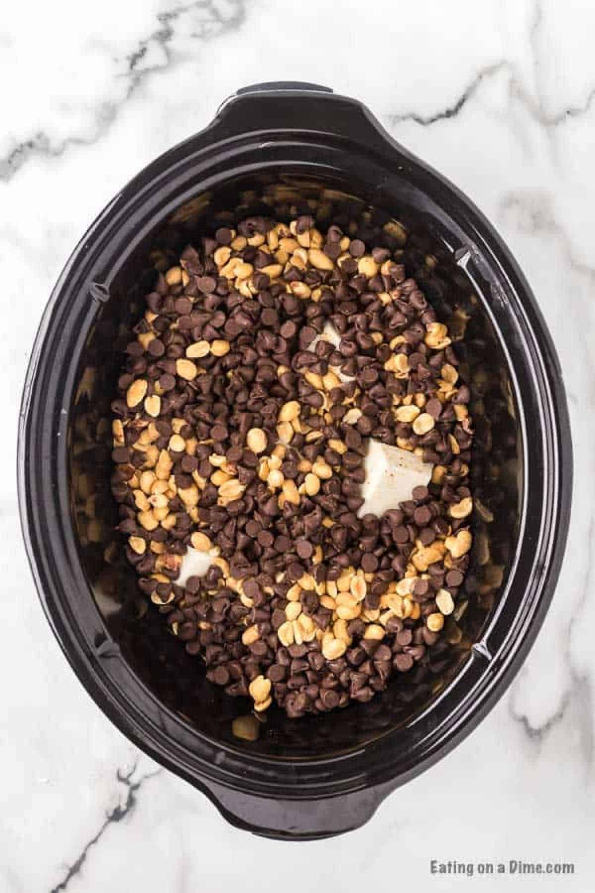 Chocolate chips and peanuts in the slow cooker topped on the almond bark