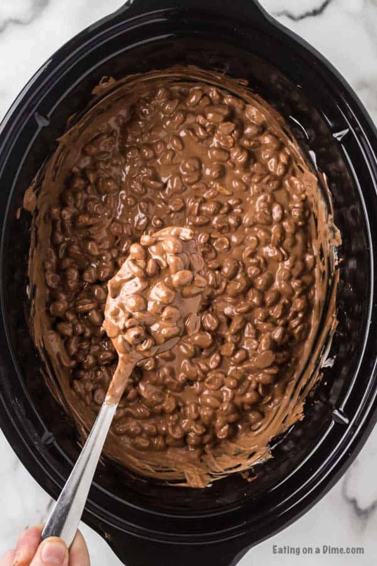 Melted chocolate mixed with peanuts with a serving on a spoon