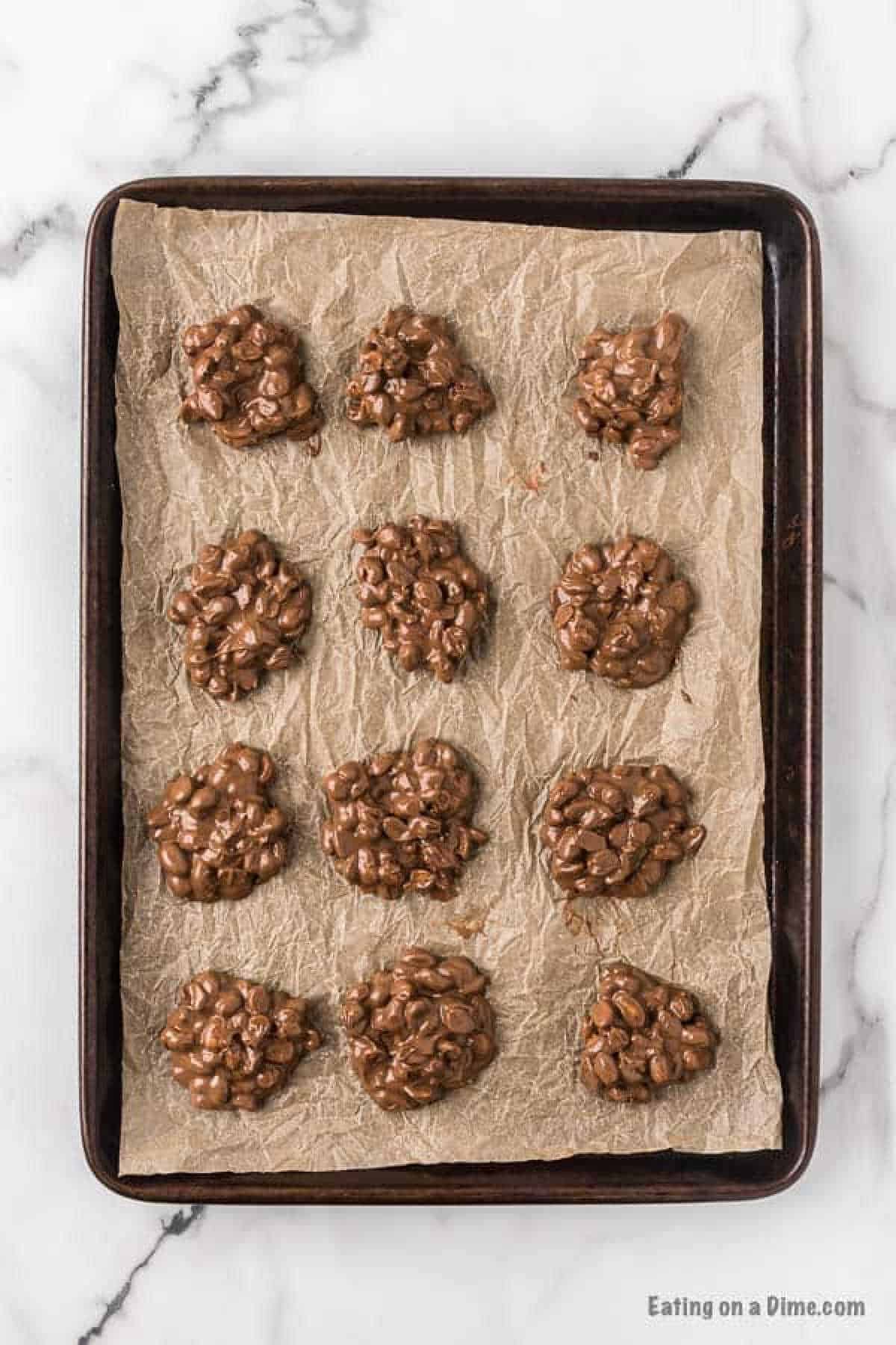 Chocolate peanut clusters on a baking sheet lined with parchment paper