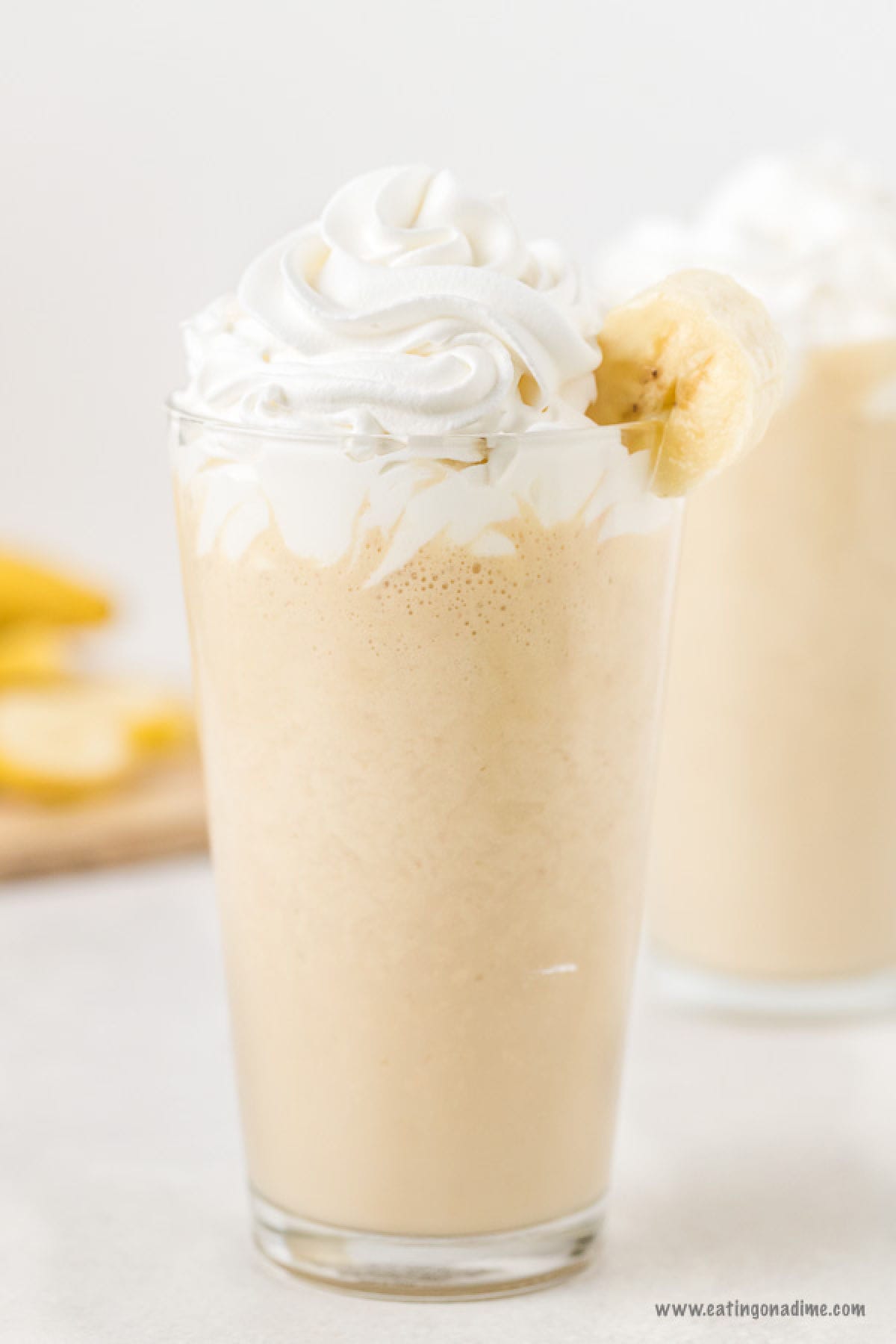 Peanut Butter Banana Smoothie in a glass topped with whipped cream and banana slices