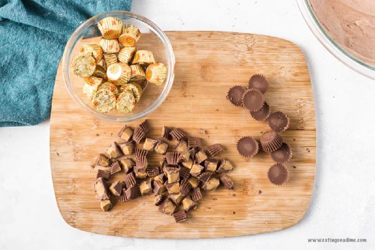 Chopping Reese's Peanut Butter cups into bite size pieces on a cutting board