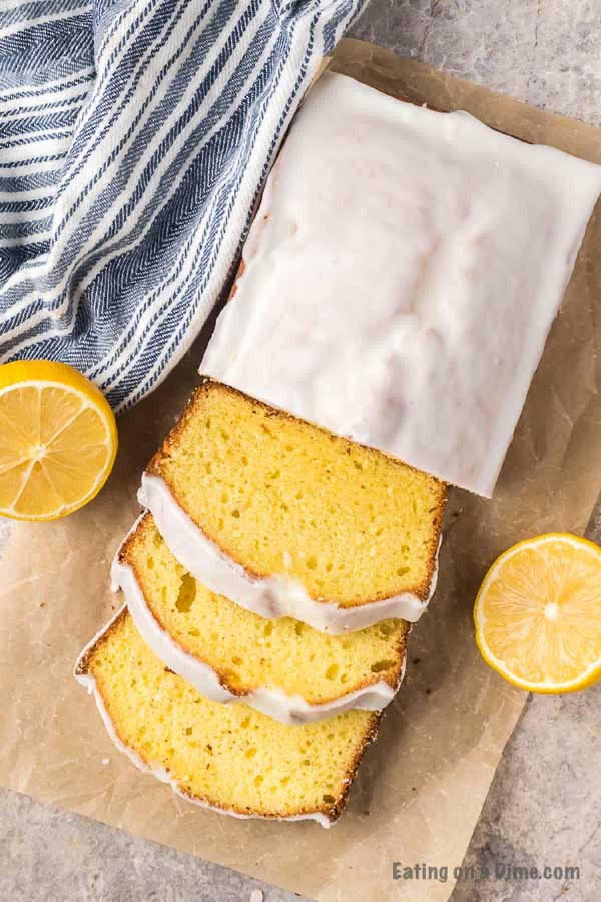 Overhead picture of lemon loaf sliced with fresh lemon halves on the side
