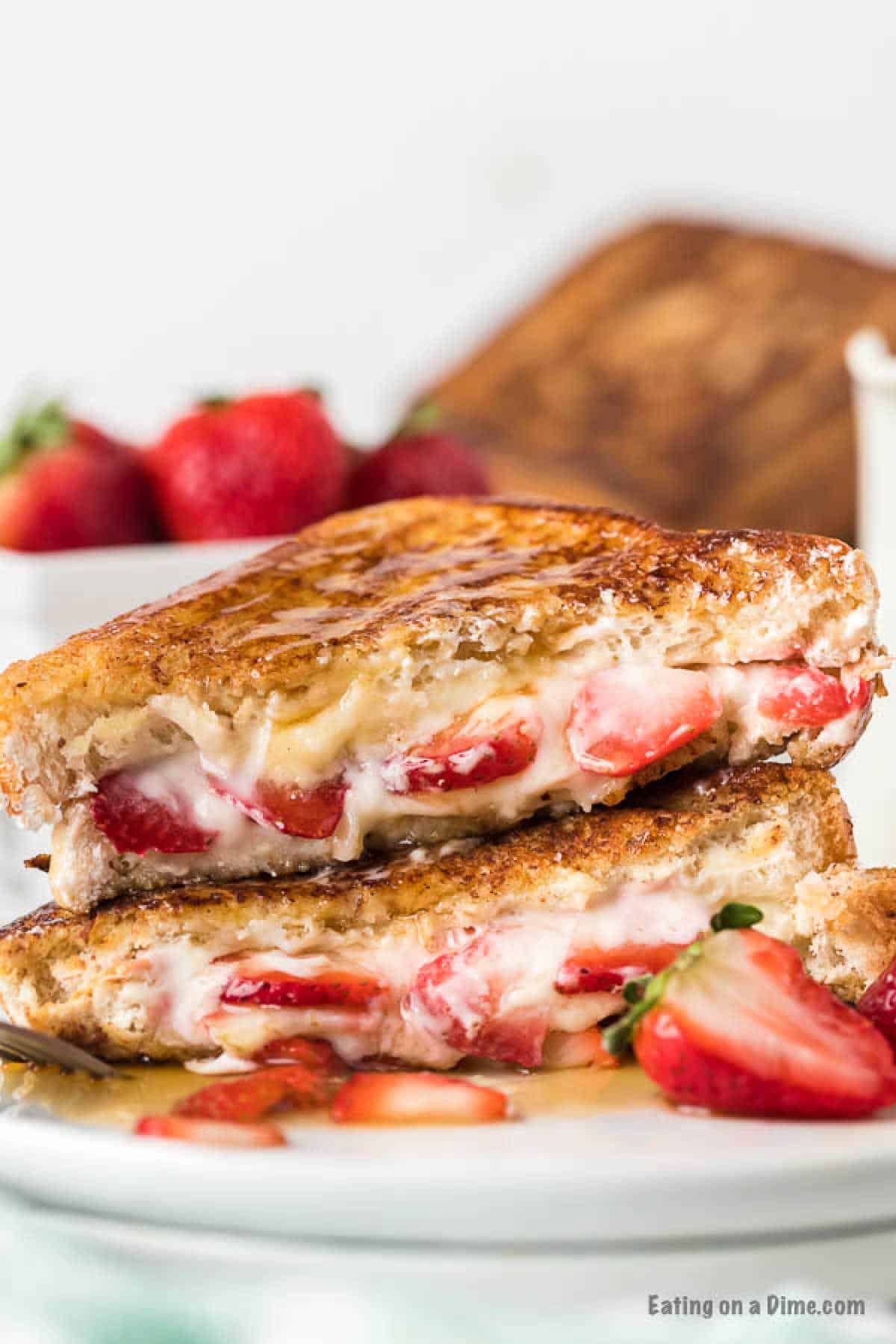 Stuffed French Toast cut in half stacked on a plate with fresh strawberries