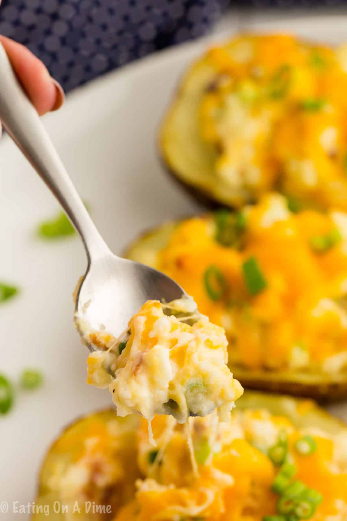 Twice baked potatoes on a baking sheet with a bite on a spoon
