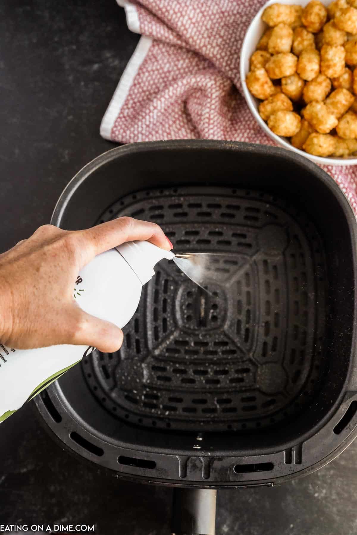Spraying the air fryer basket with cooking spray