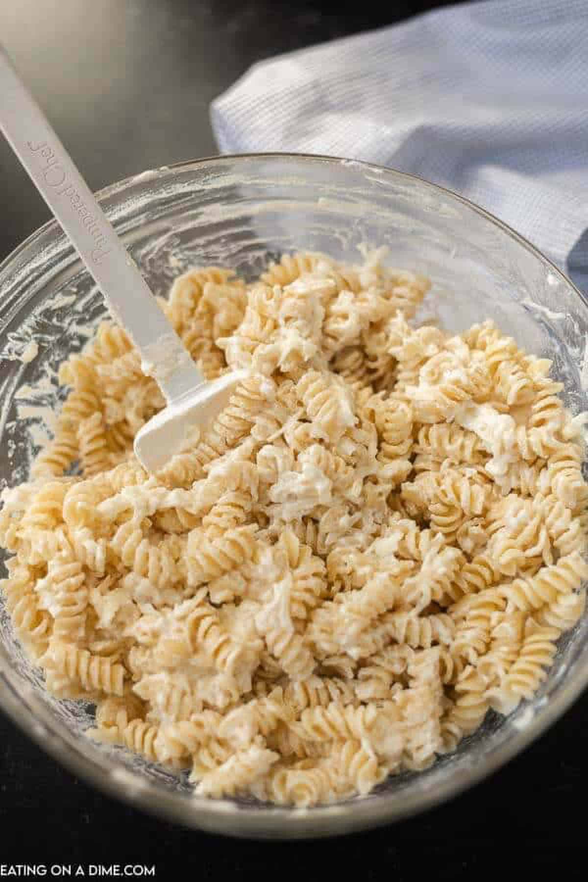 Mixed in cooked rotini pasta in the ricotta cheese mixture in a bowl with a spatula