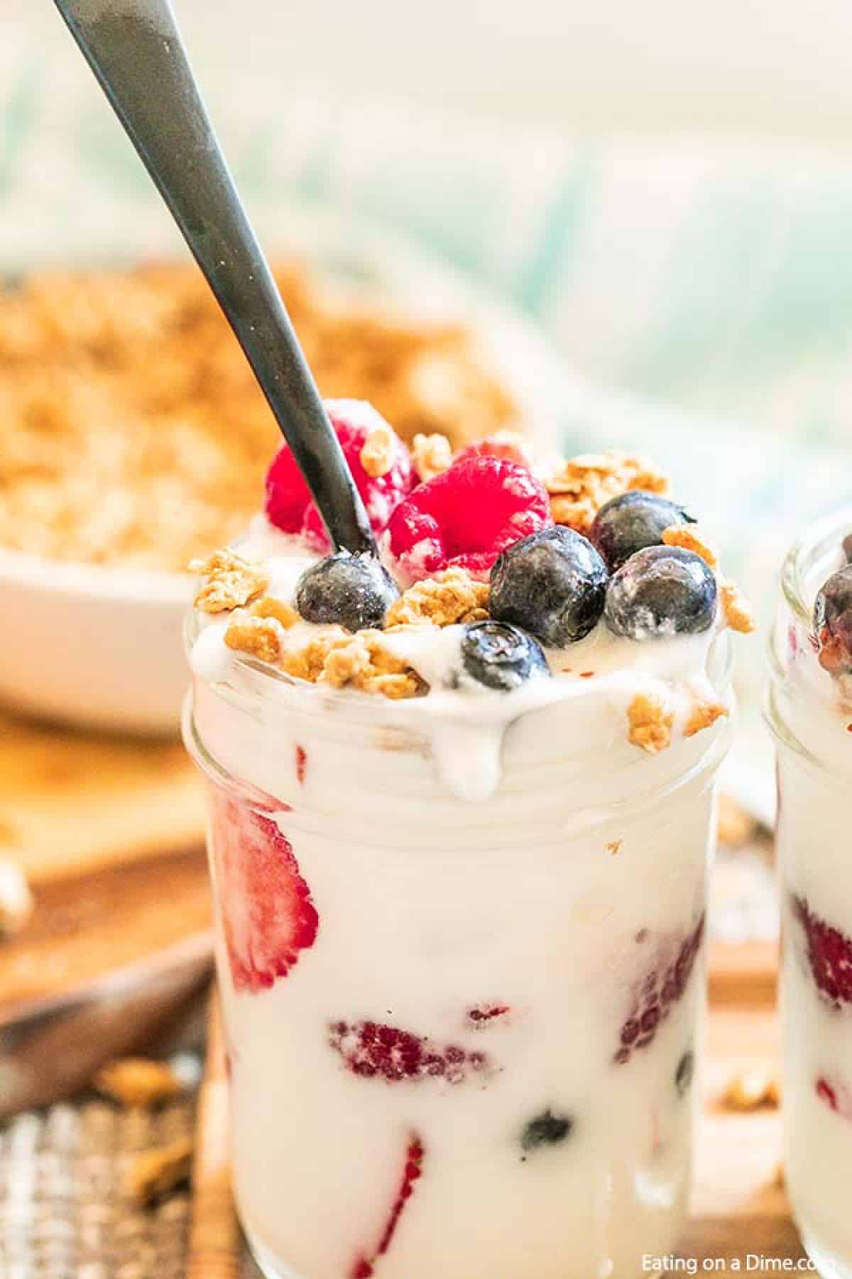 Fruit and Yogurt parfait in a mason jar topped with blueberries, raspberries and granola with a spoon