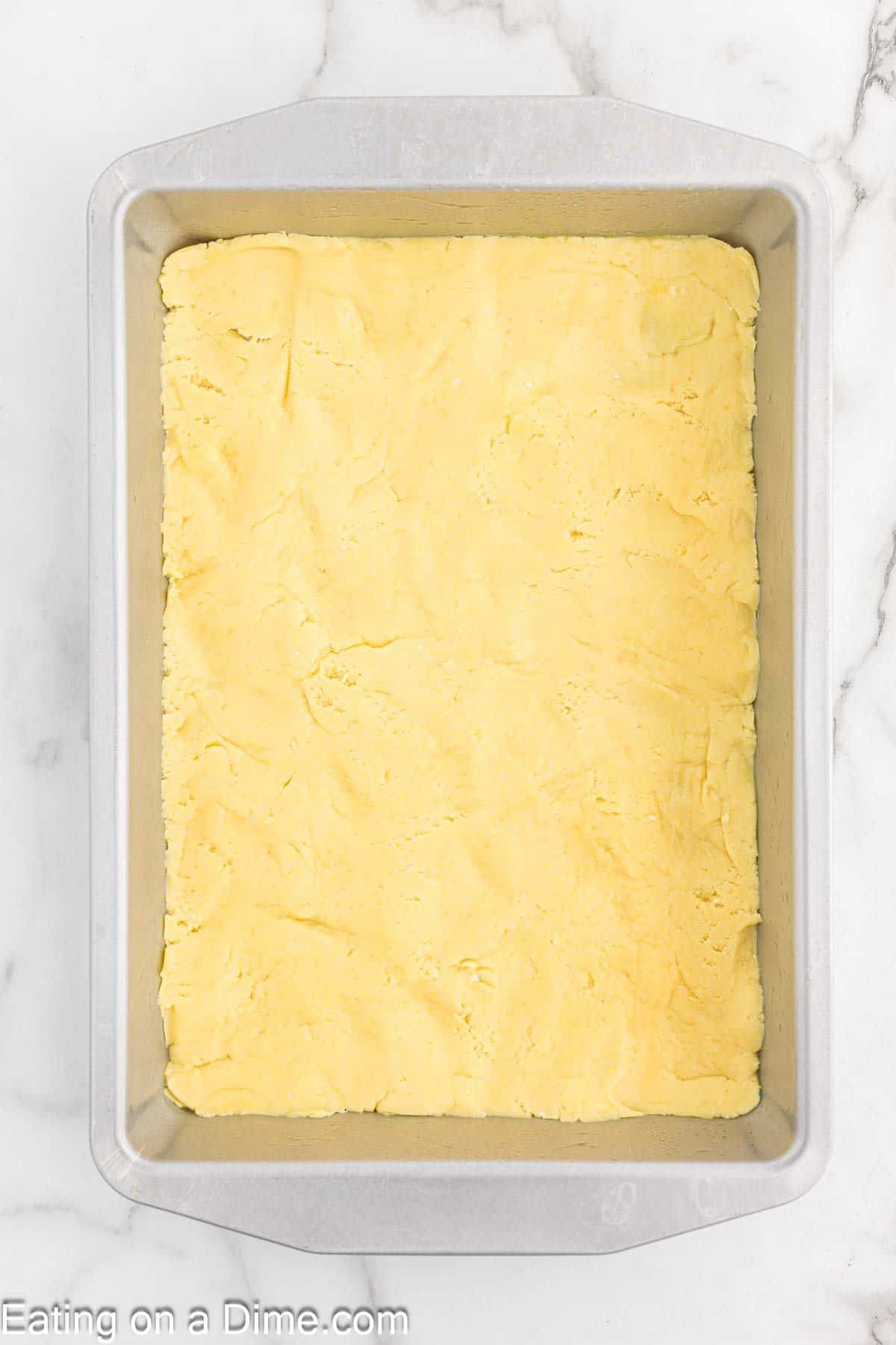 Spreading the cake mix batter in a baking dish