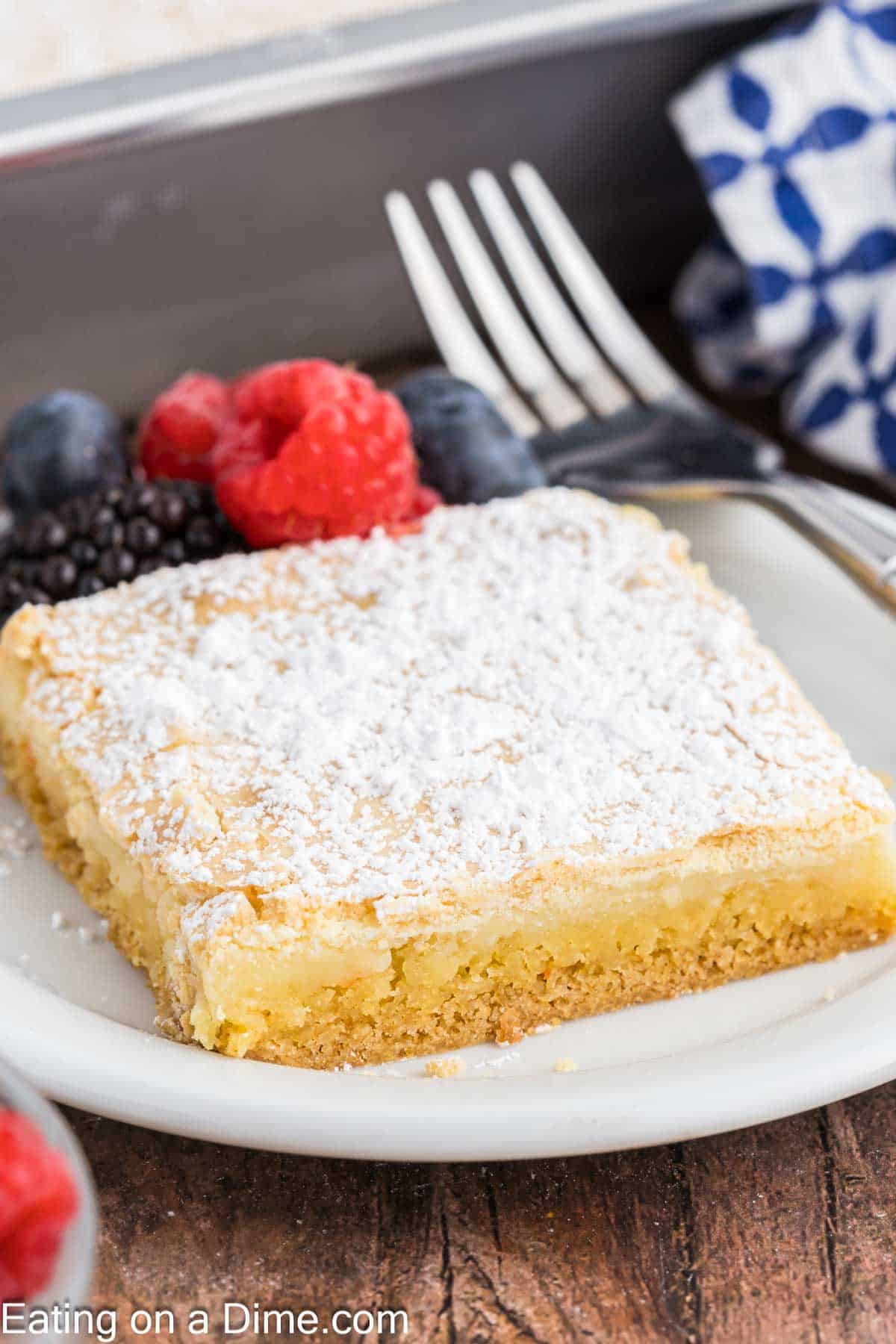 Slice of butter cake on a plate with a side of raspberries, blueberries and blackberries