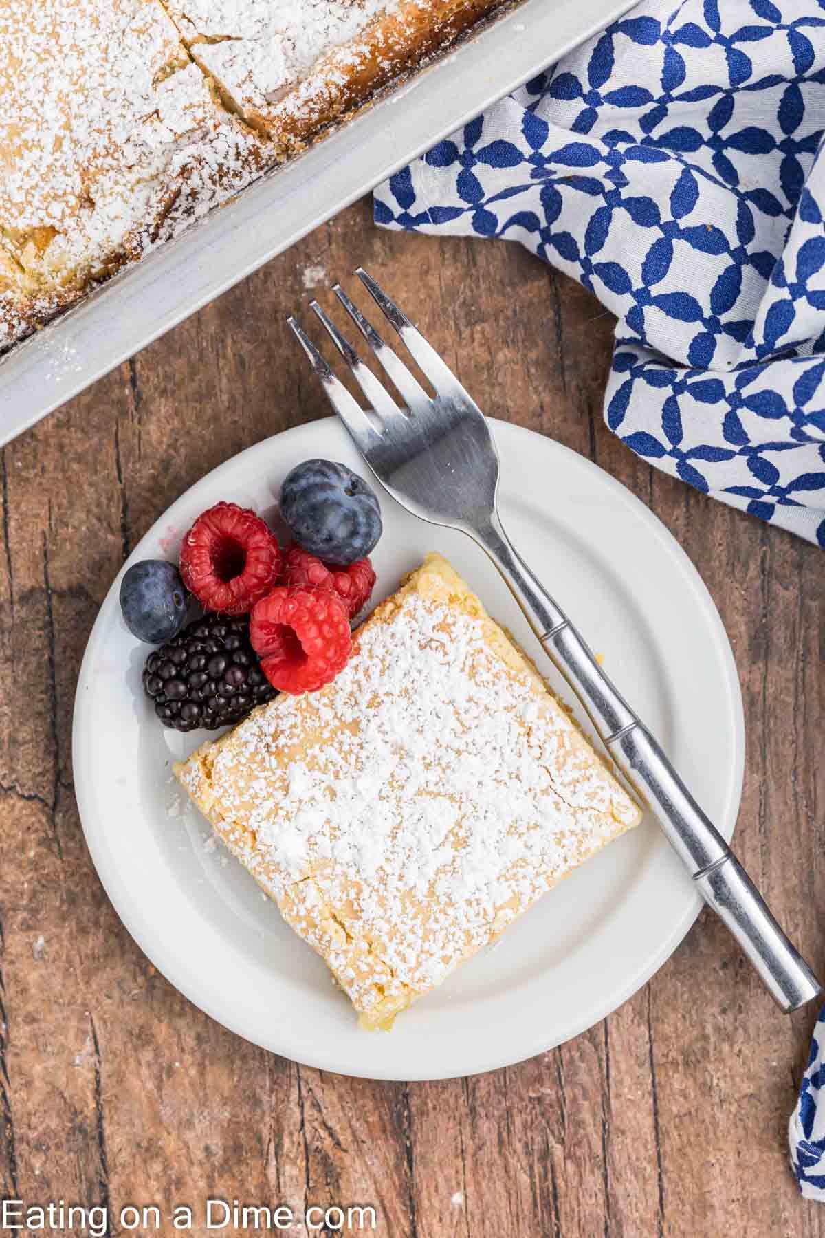 Slice of butter cake on a plate with a side of raspberries, blueberries, and blackberries