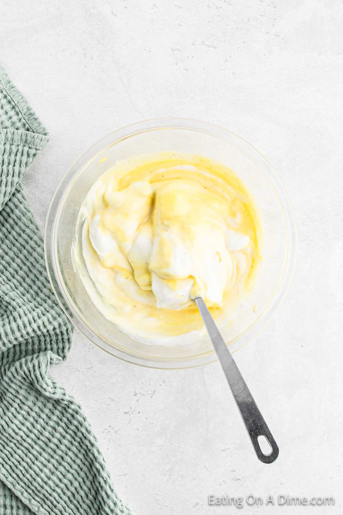 Beating the egg mixture with the egg white mixture in a bowl with a spoon