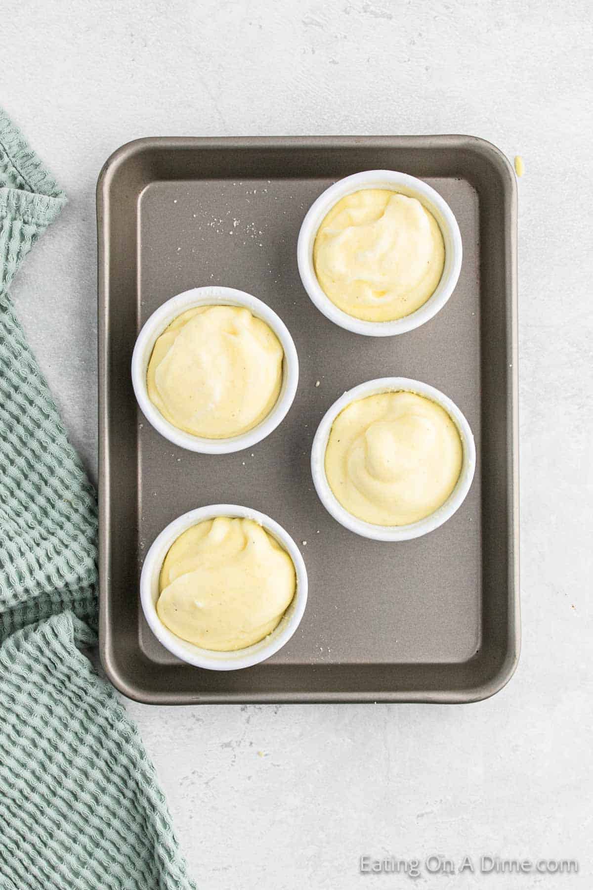 Dividing the egg mixture into small ramekins on a baking sheet