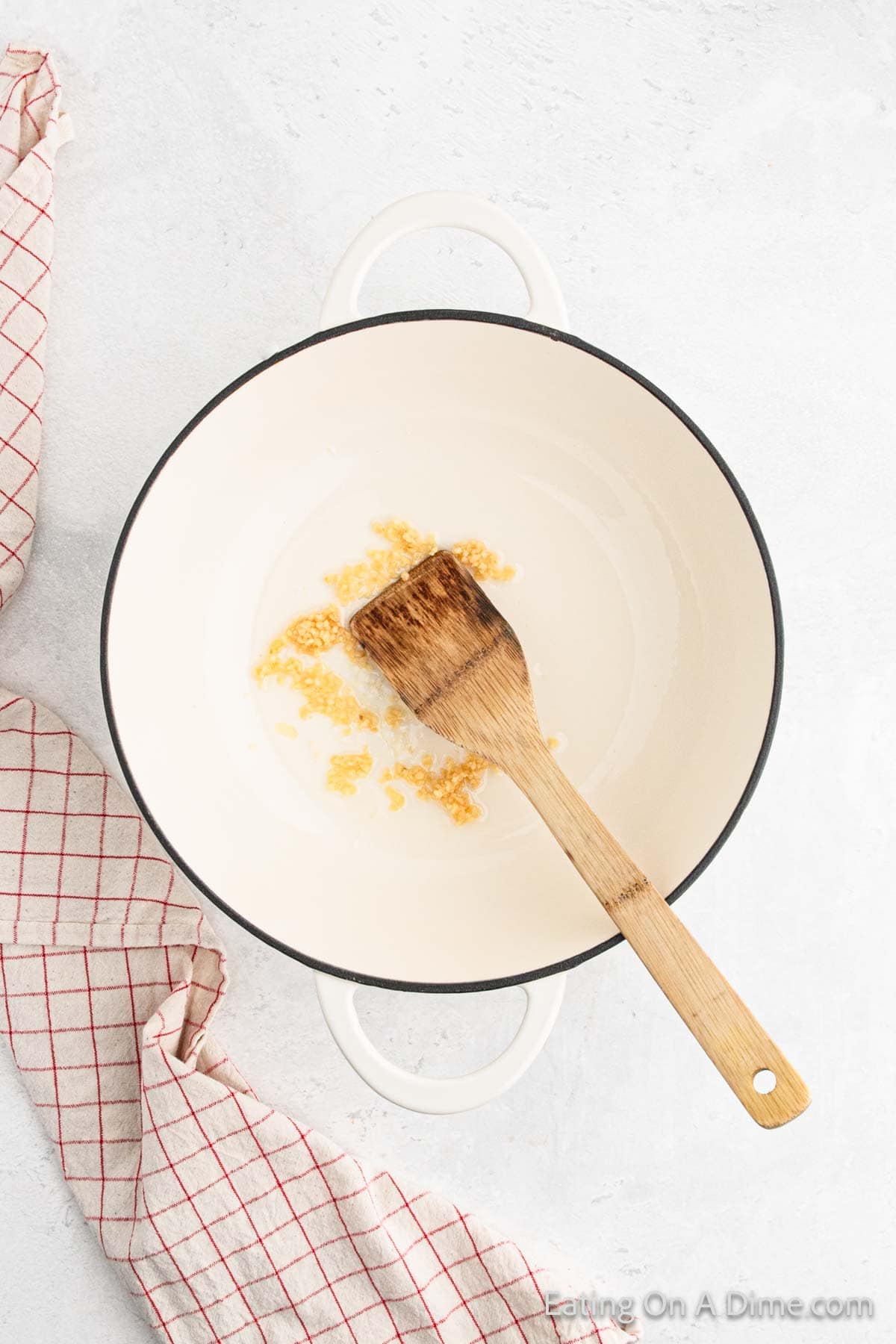 Cooking minced garlic in a sauce pan with wooden spoon