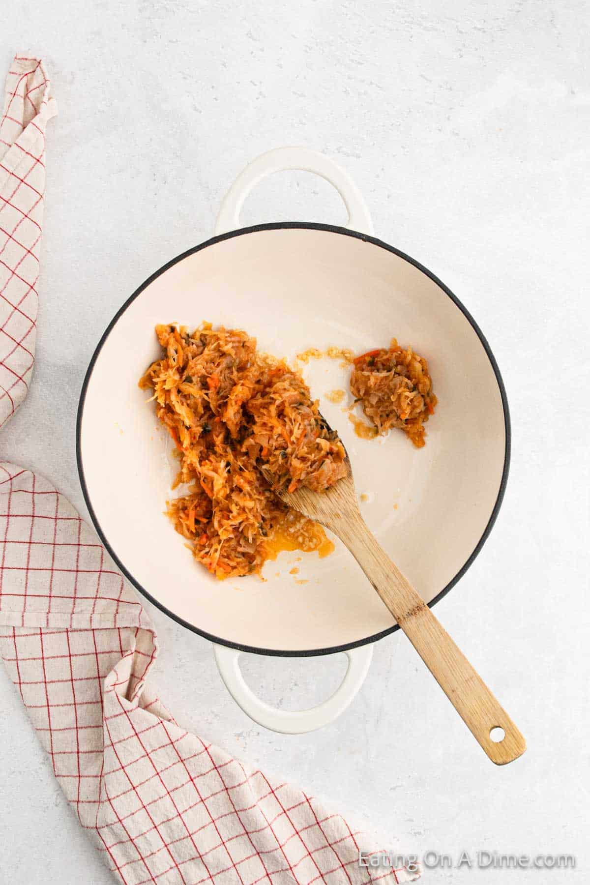 Adding the kimchi to the sauce pan with the wooden spoon