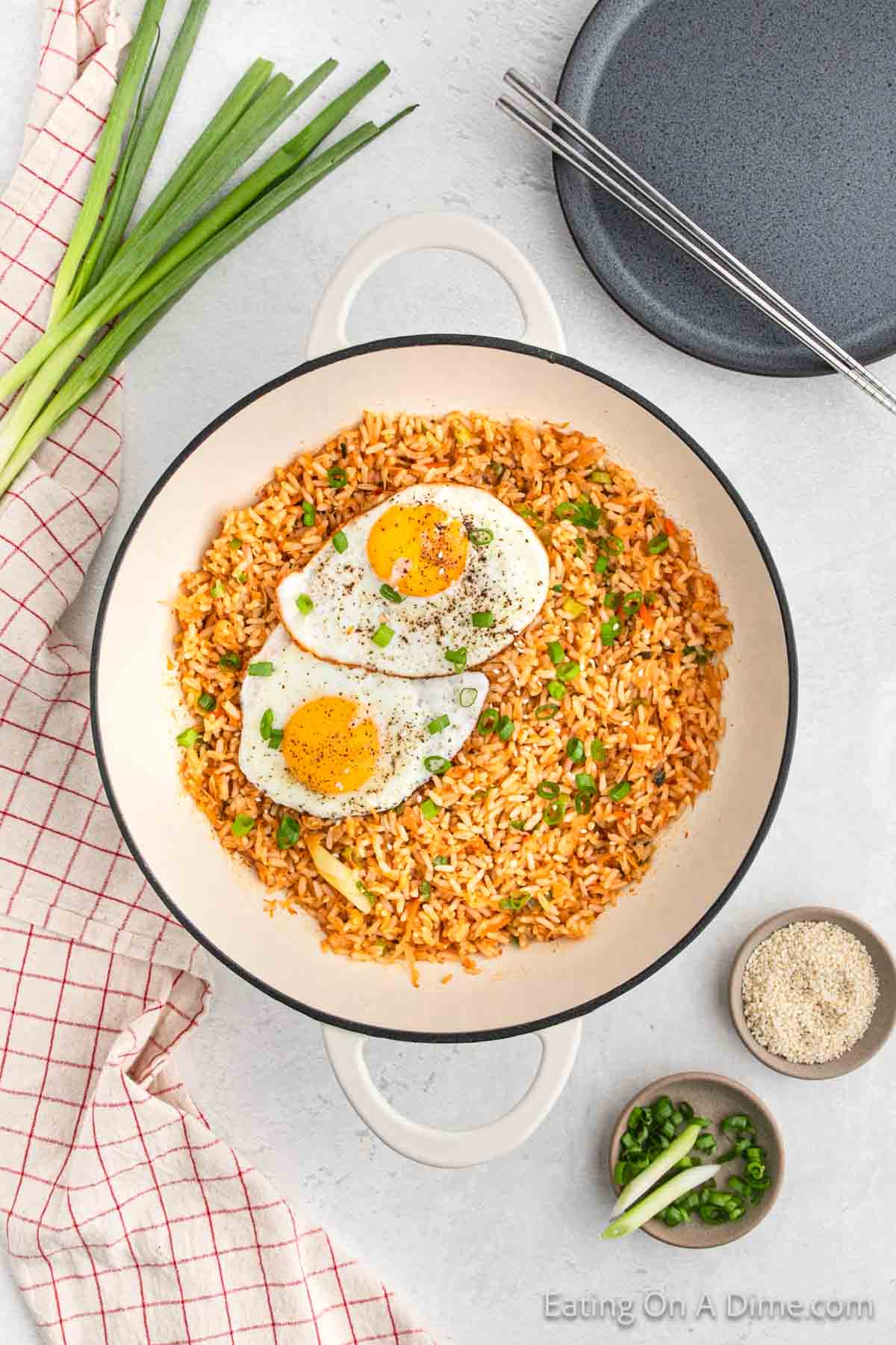 Kimchi rice in a large pan topped with two fried eggs and chopped green onions