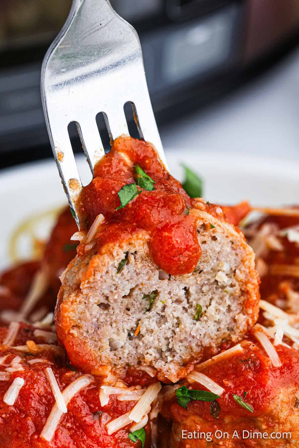 Meatball cut in half on a fork with spaghetti and sauce