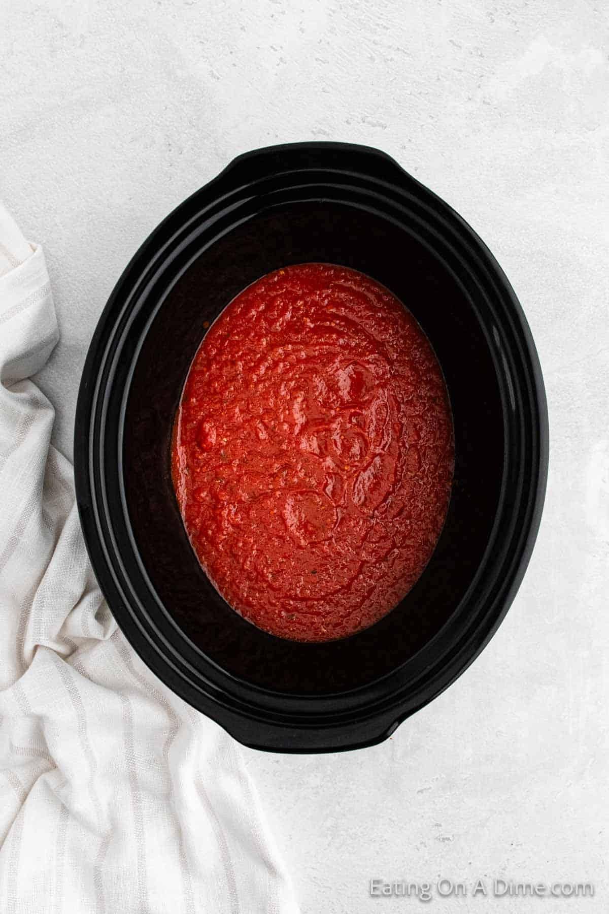 Marinara sauce in the bottom of the slow cooker