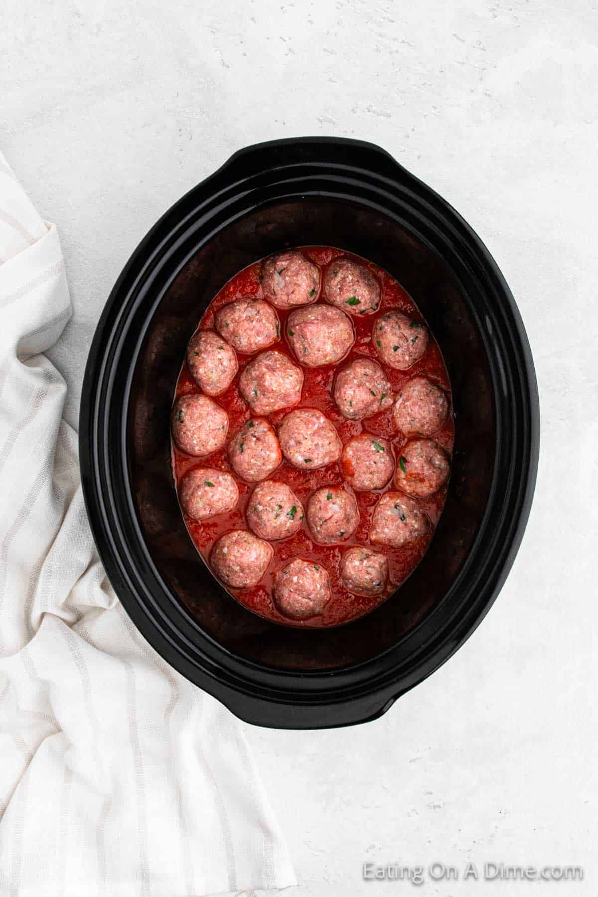 Topping the marinara sauce with uncooked meatballs in the slow cooker