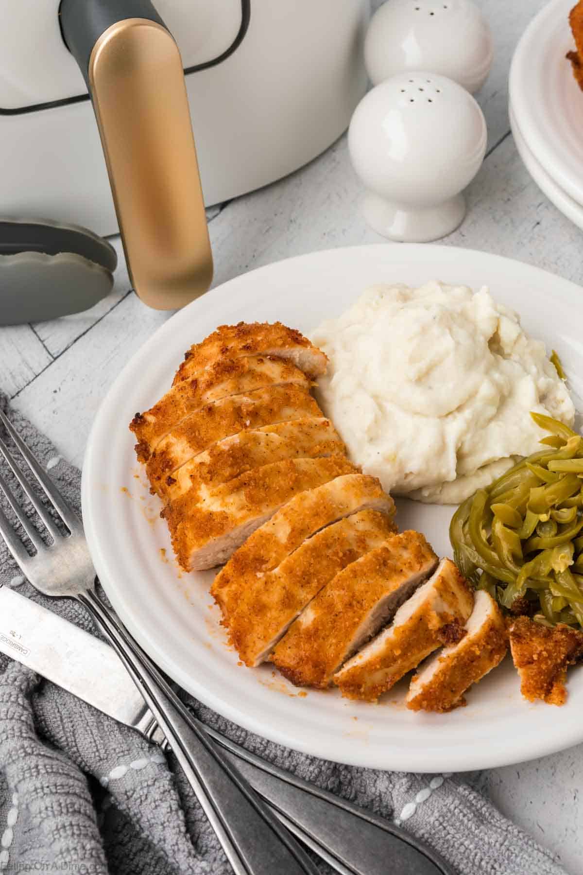 Shake and Bake cooked chicken sliced on a plate with mashed potatoes and green beans