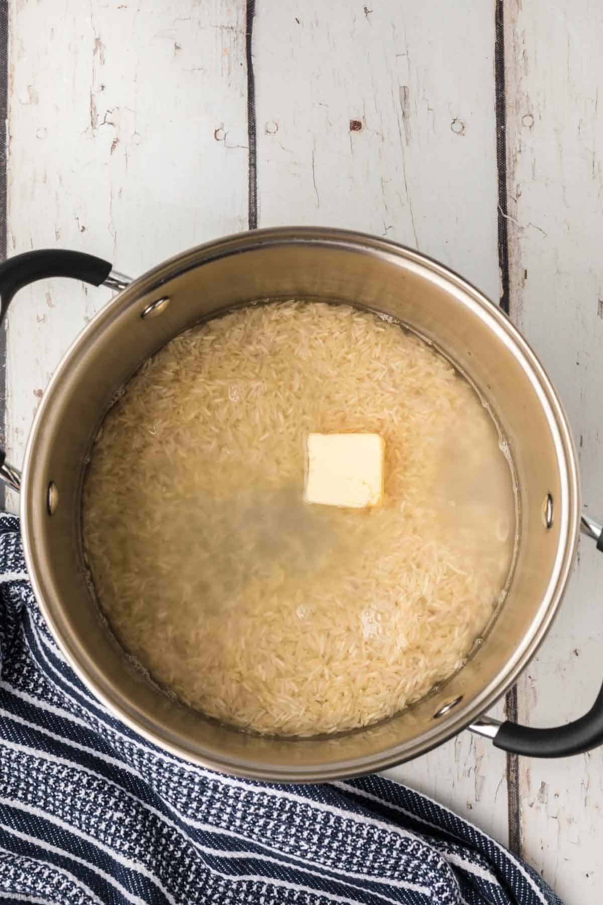 Large pot with rice covered with water and butter