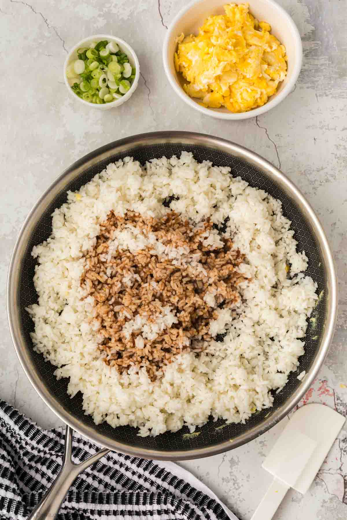 Sauce drizzled over the white rice and small bowls of scrambled eggs and green onions